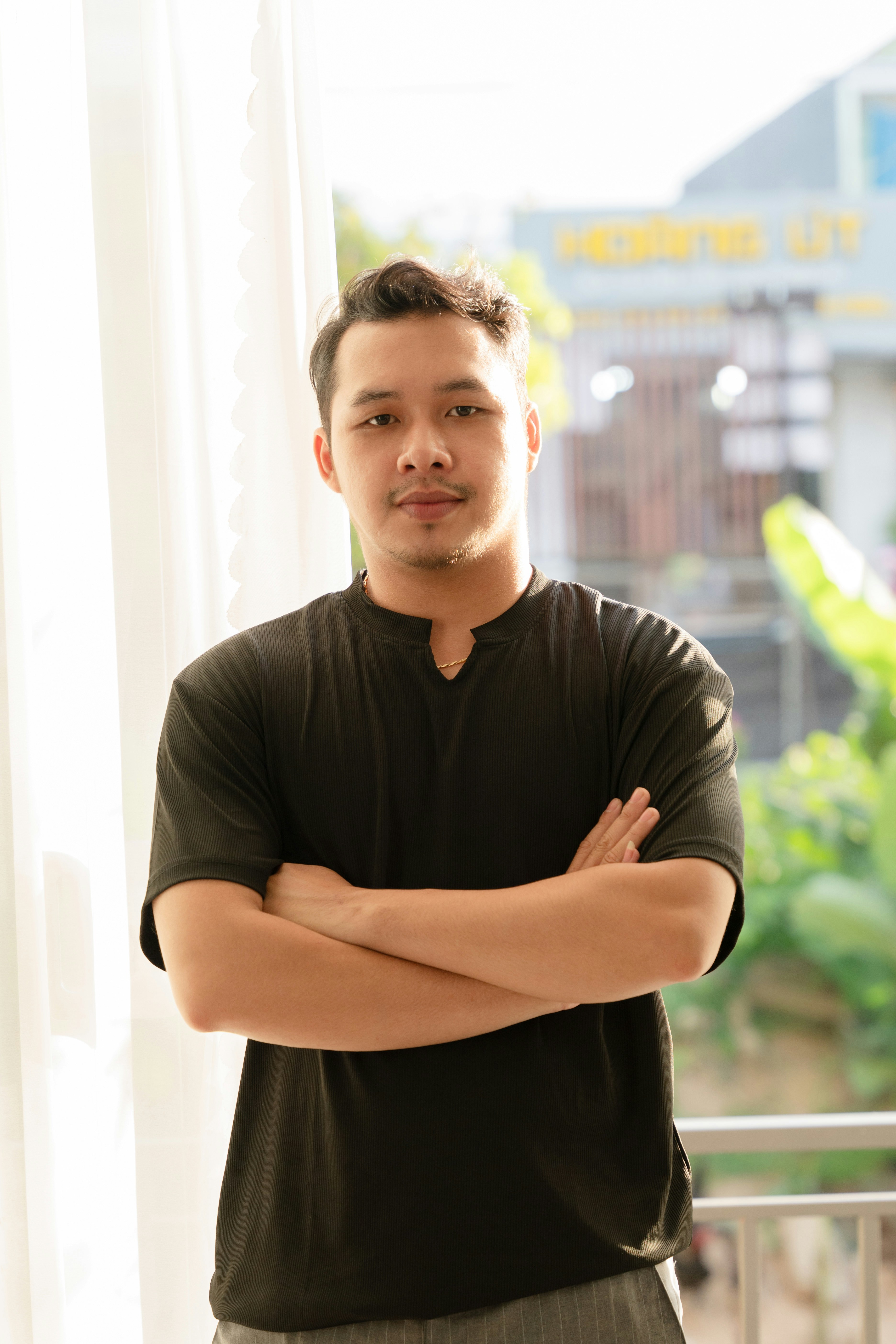 Seorang pria berdiri di depan jendela dengan tangan disilangkan