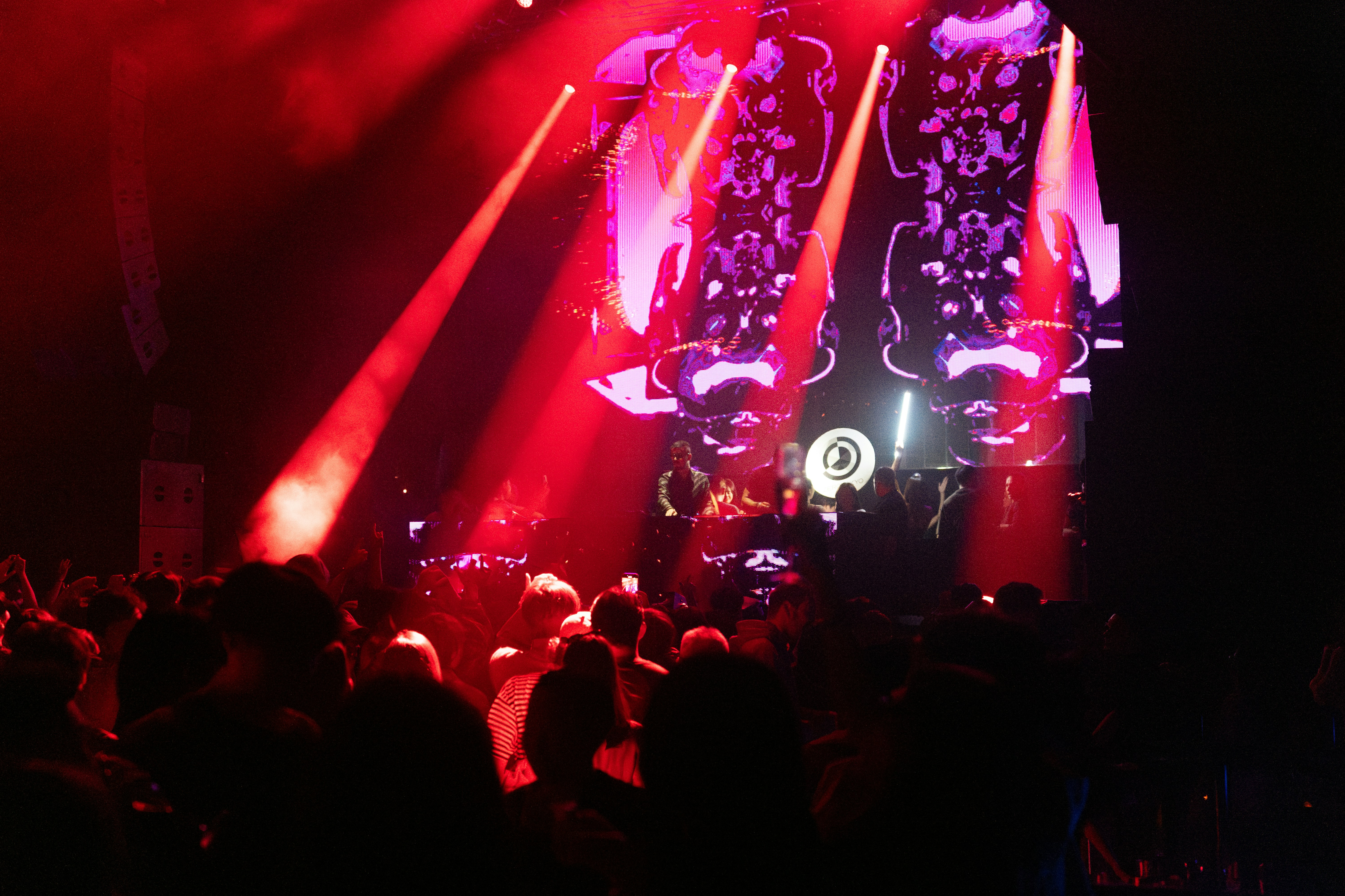 Crowd at concert with colorful stage lighting and DJ on stage