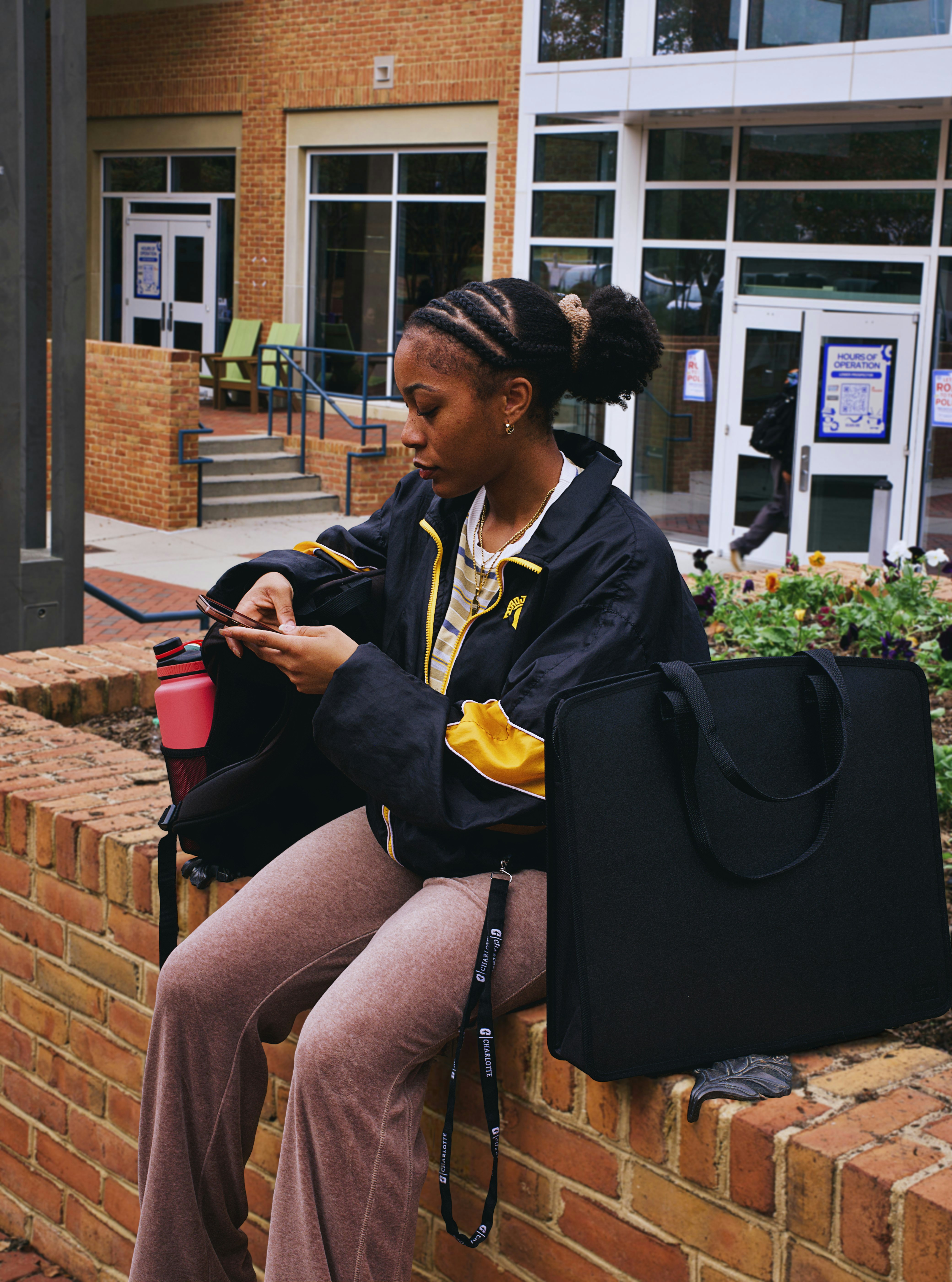A woman sitting on a brick wall looking at her cell phone