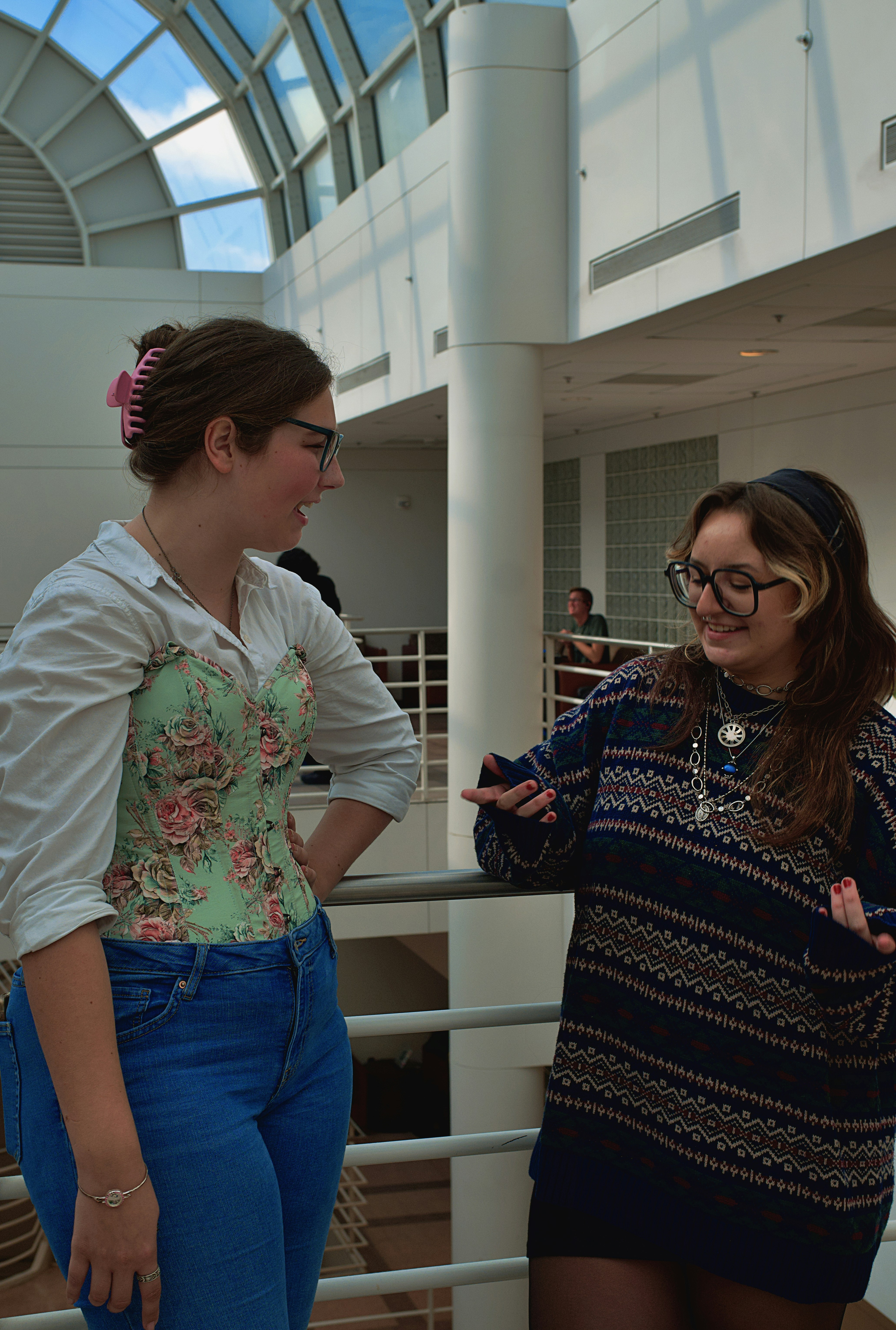 Two women in professional attire engaged in a thoughtful conversation in a bright, modern environment