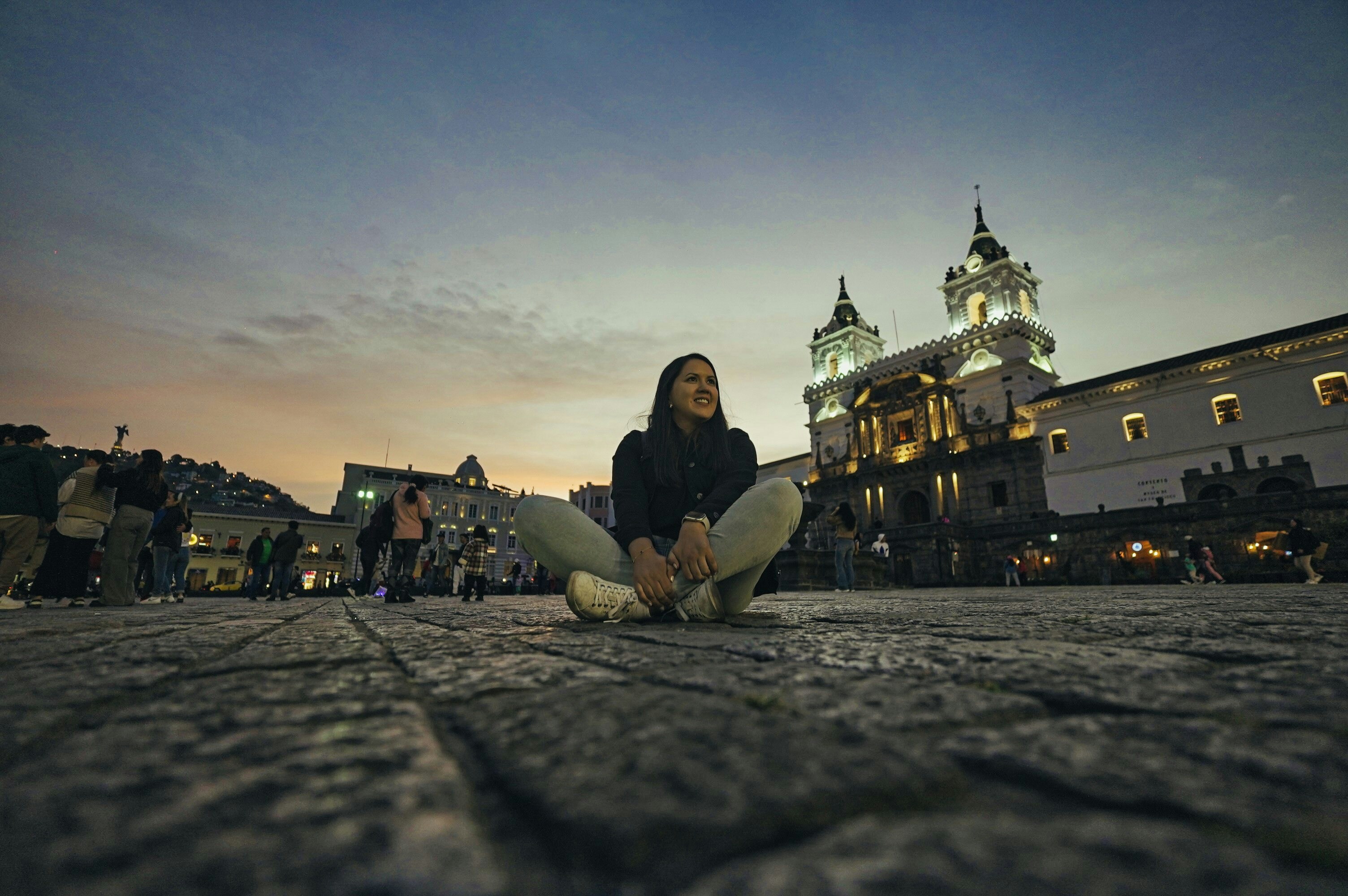A woman sitting on the ground in front of a building