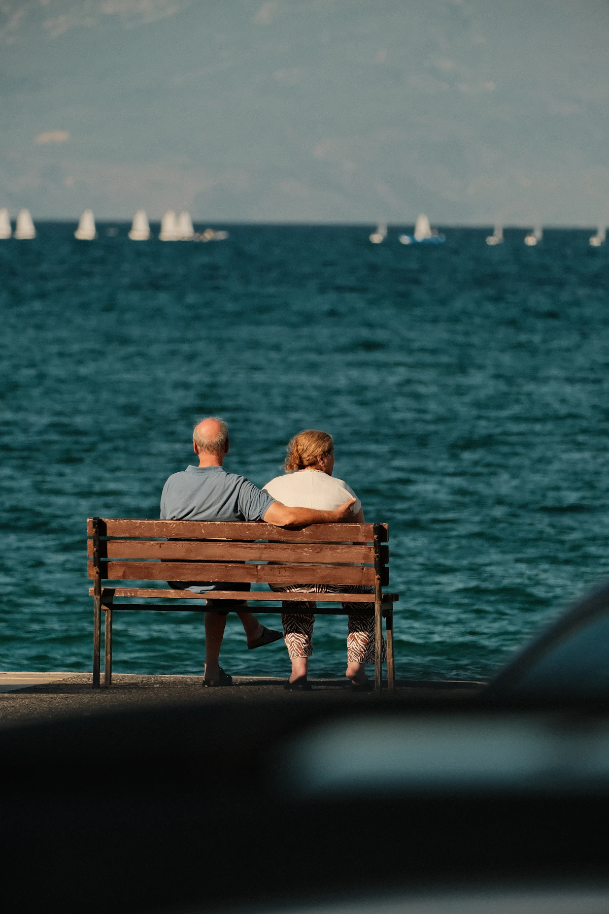 A retired couple sitting on a bench looking out over the water