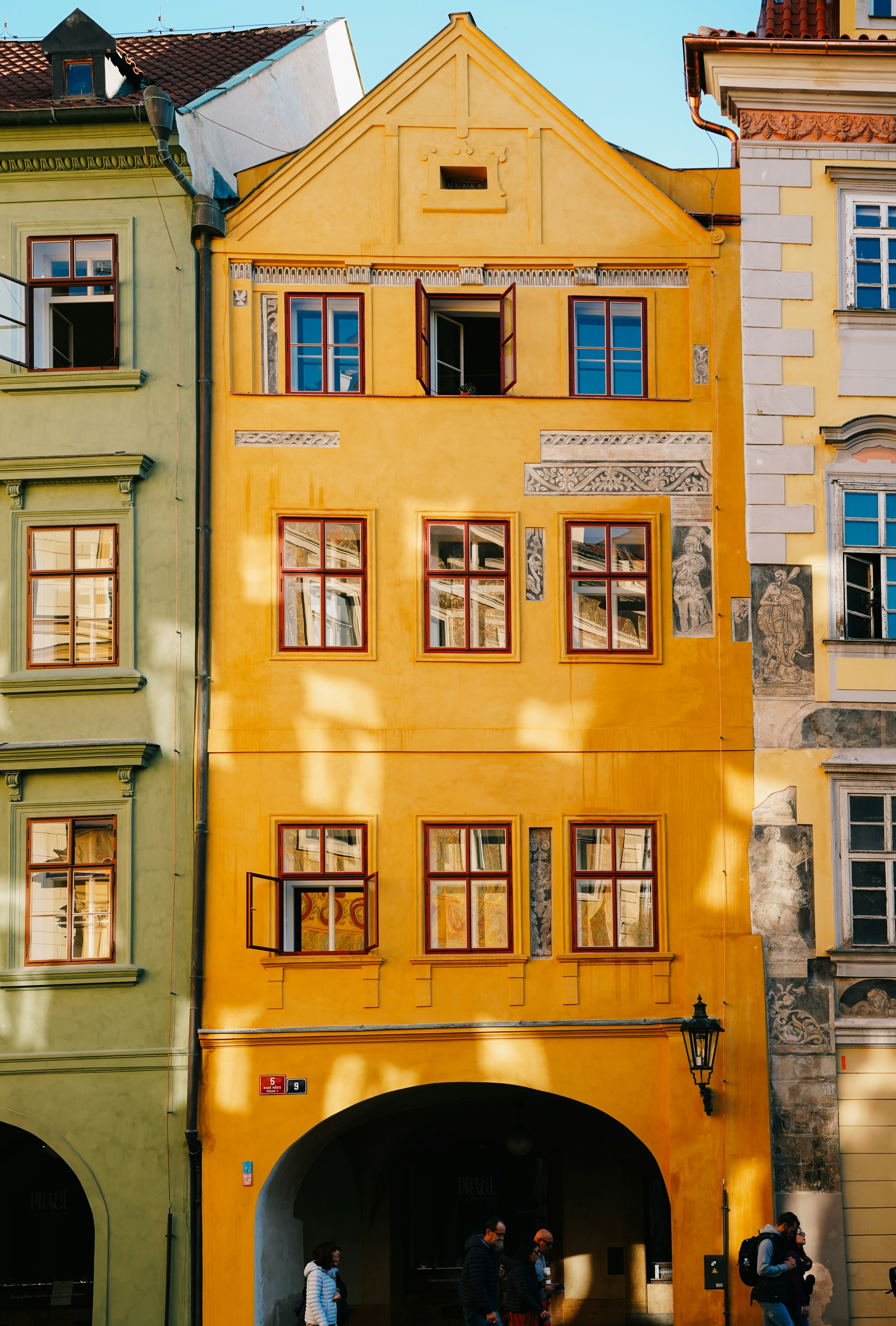 A group of people standing in front of a yellow building