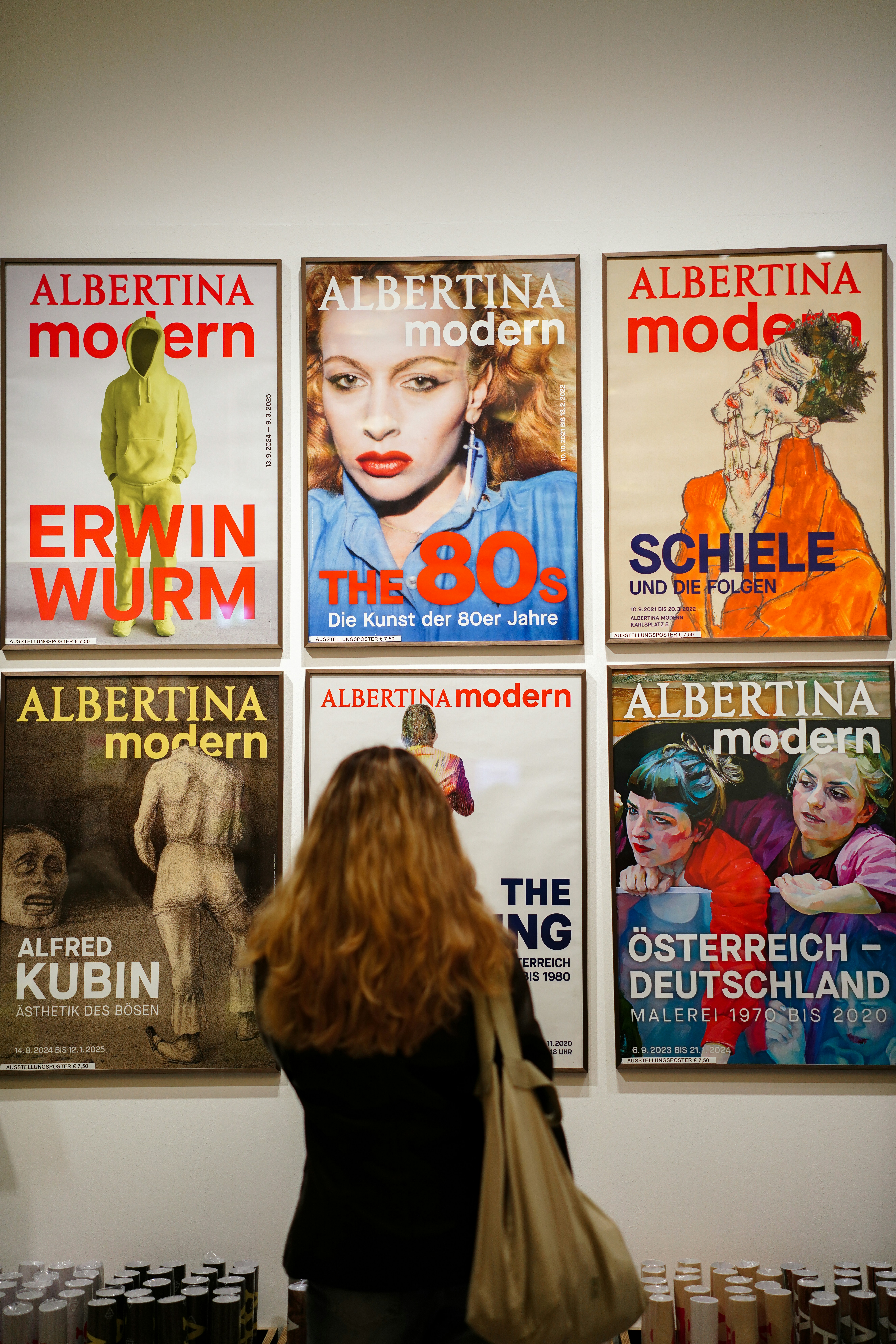 A woman standing in front of a wall with posters on it