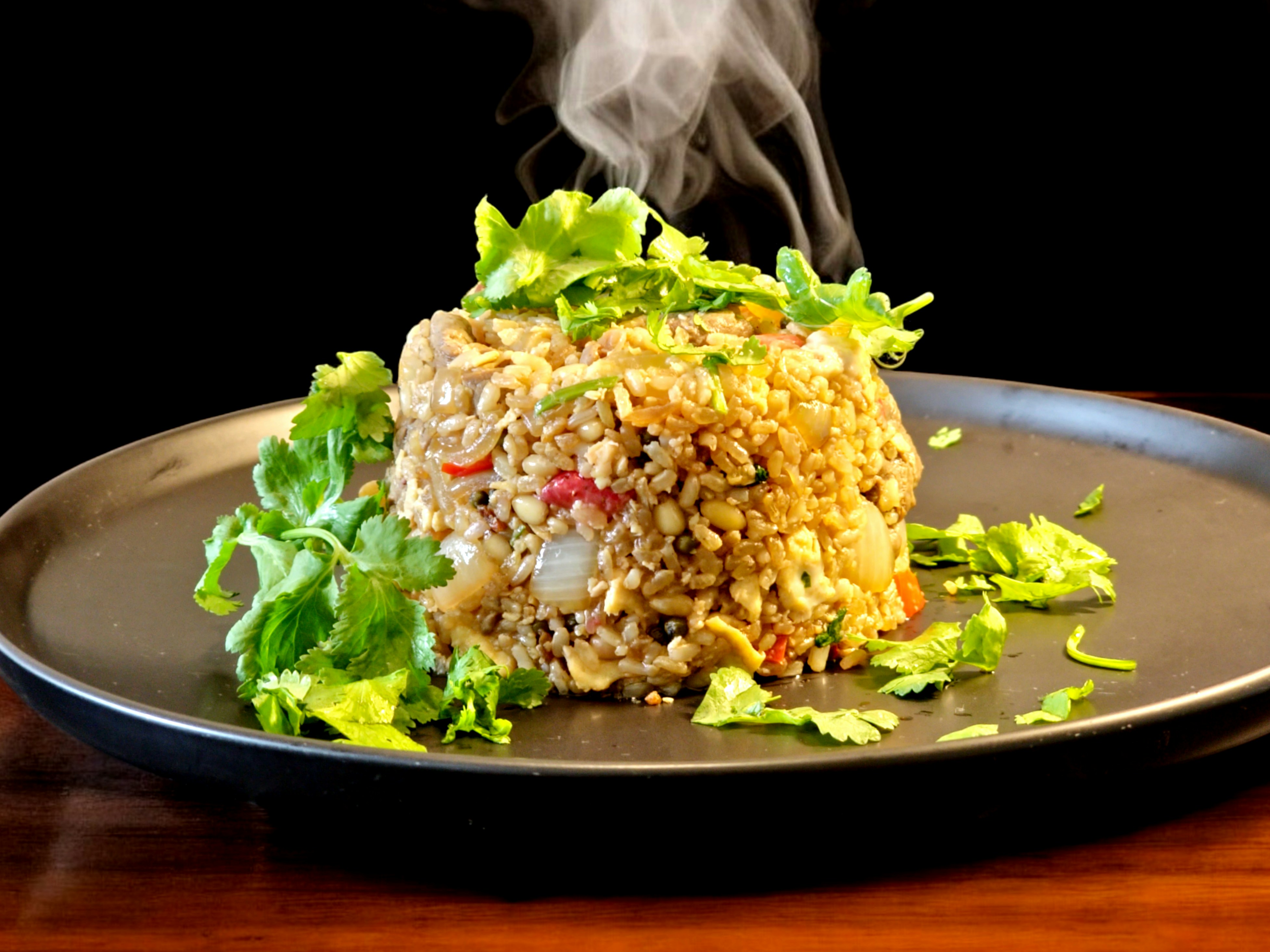 Steamed white khichu on a green leaf plate with chili oil, dark atmospheric background kitchen