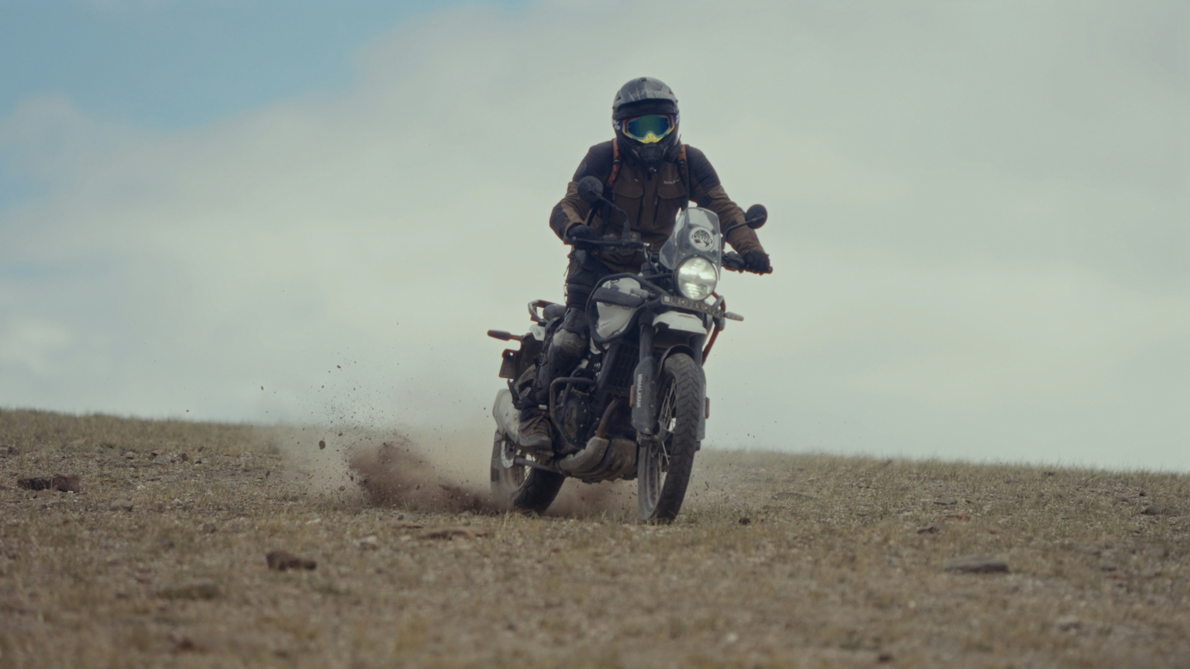 A man riding a motorcycle on top of a dry grass field