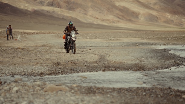 A man riding a motorcycle down a dirt road