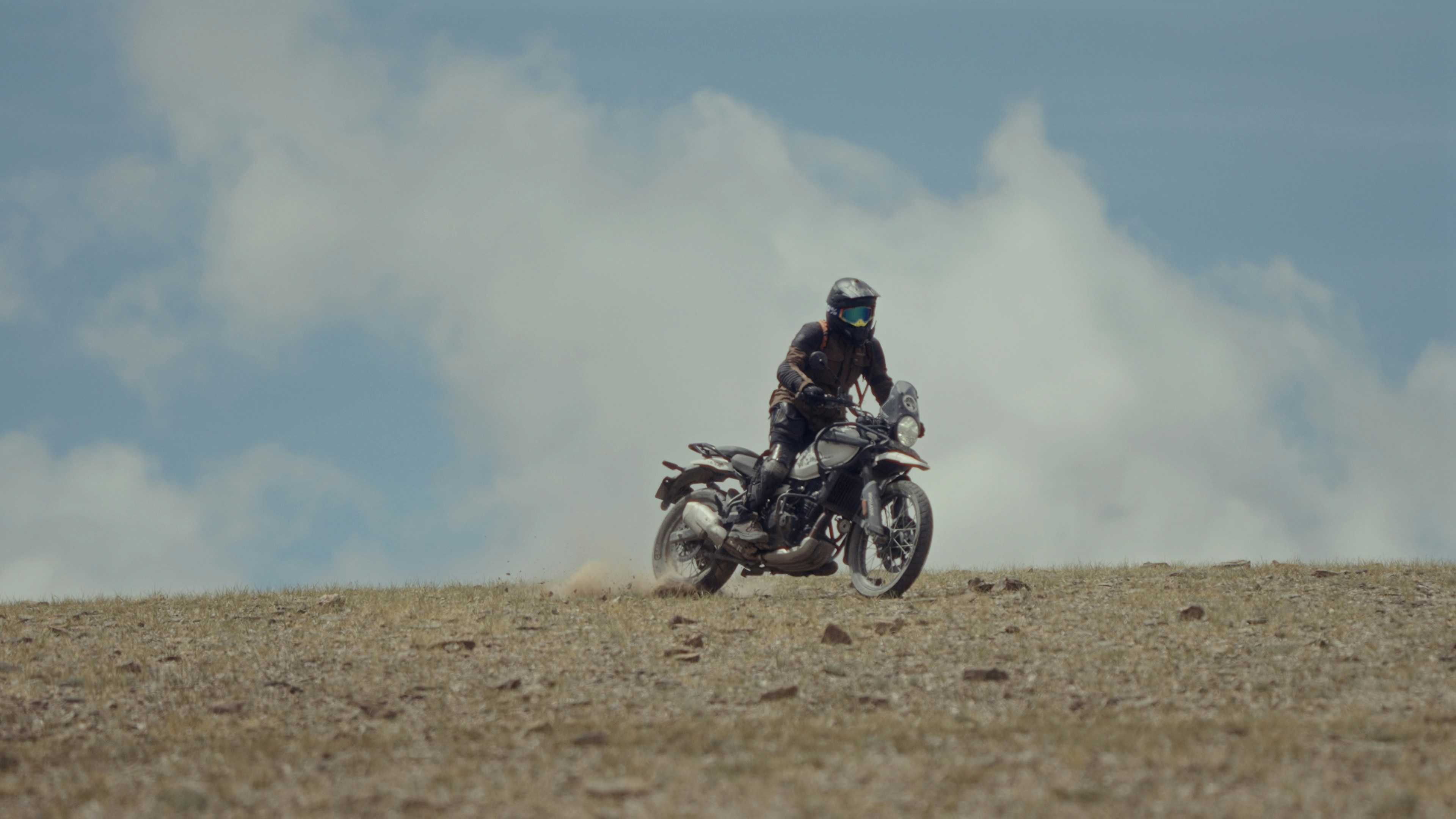 A man riding a motorcycle on top of a dry grass field