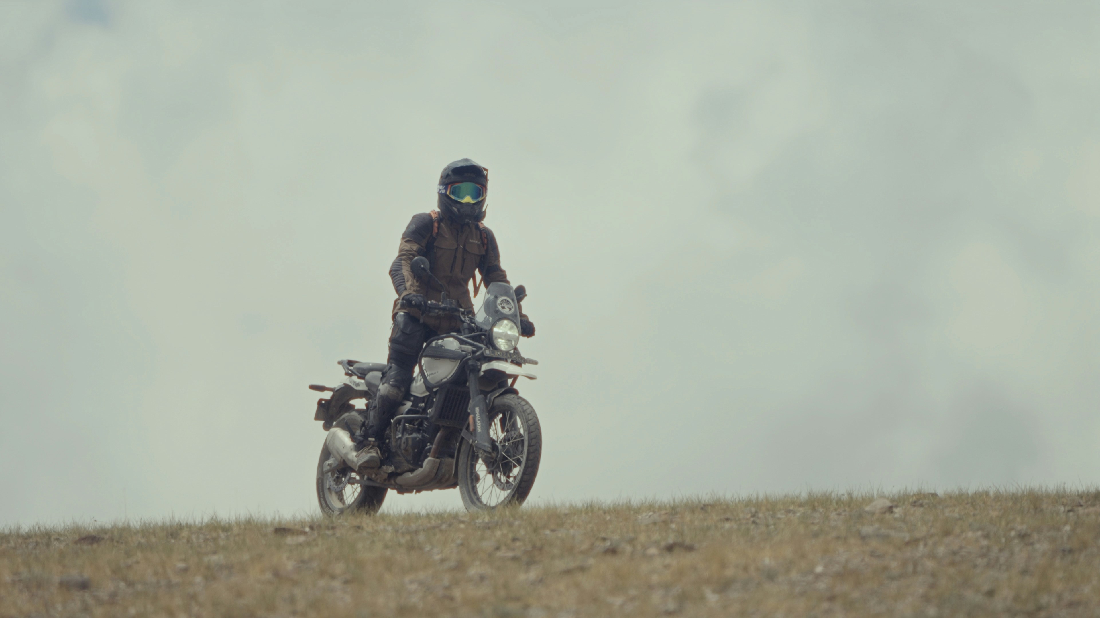 A man riding a motorcycle on top of a dry grass field