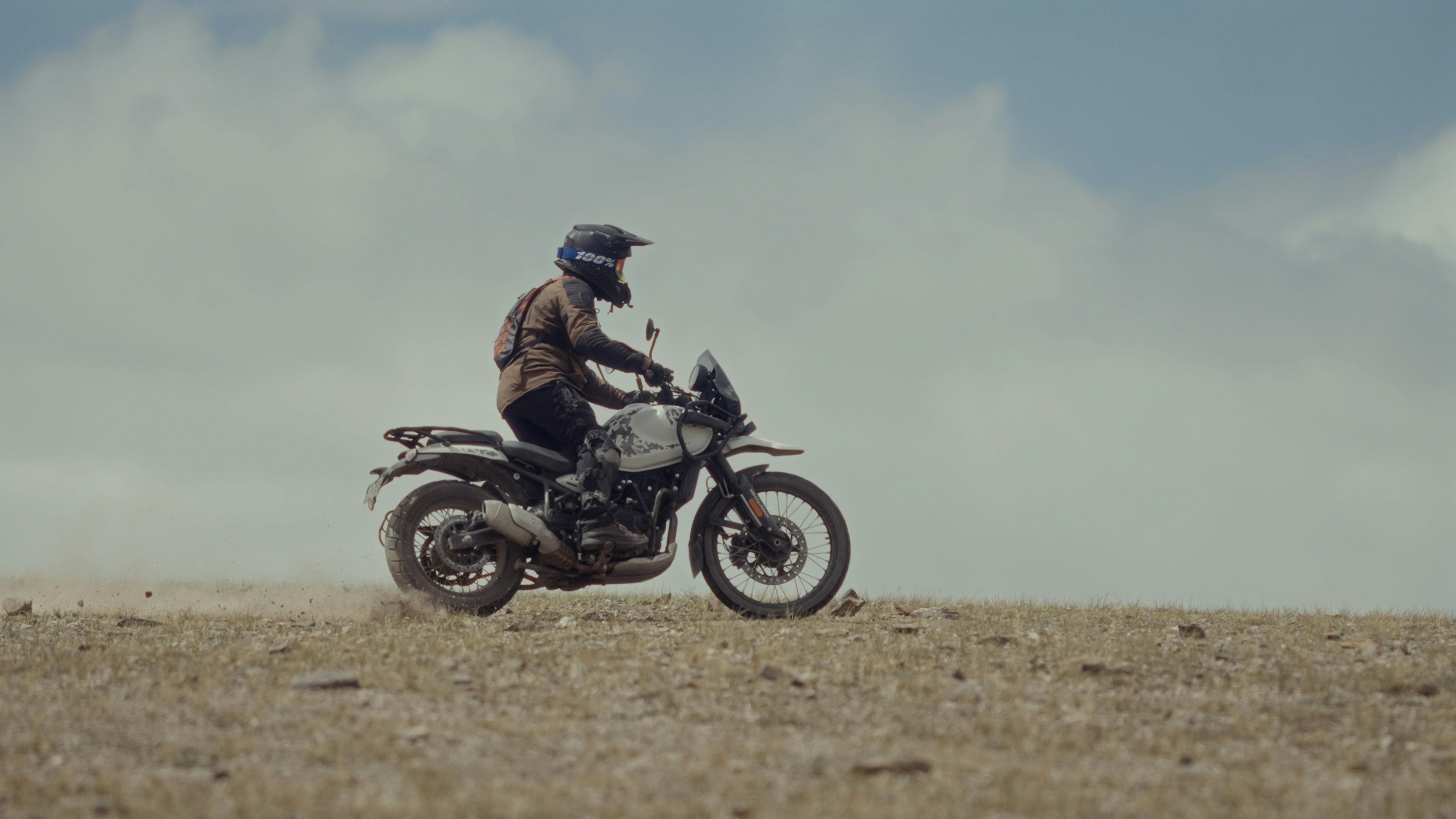 A man riding a motorcycle on top of a dry grass field