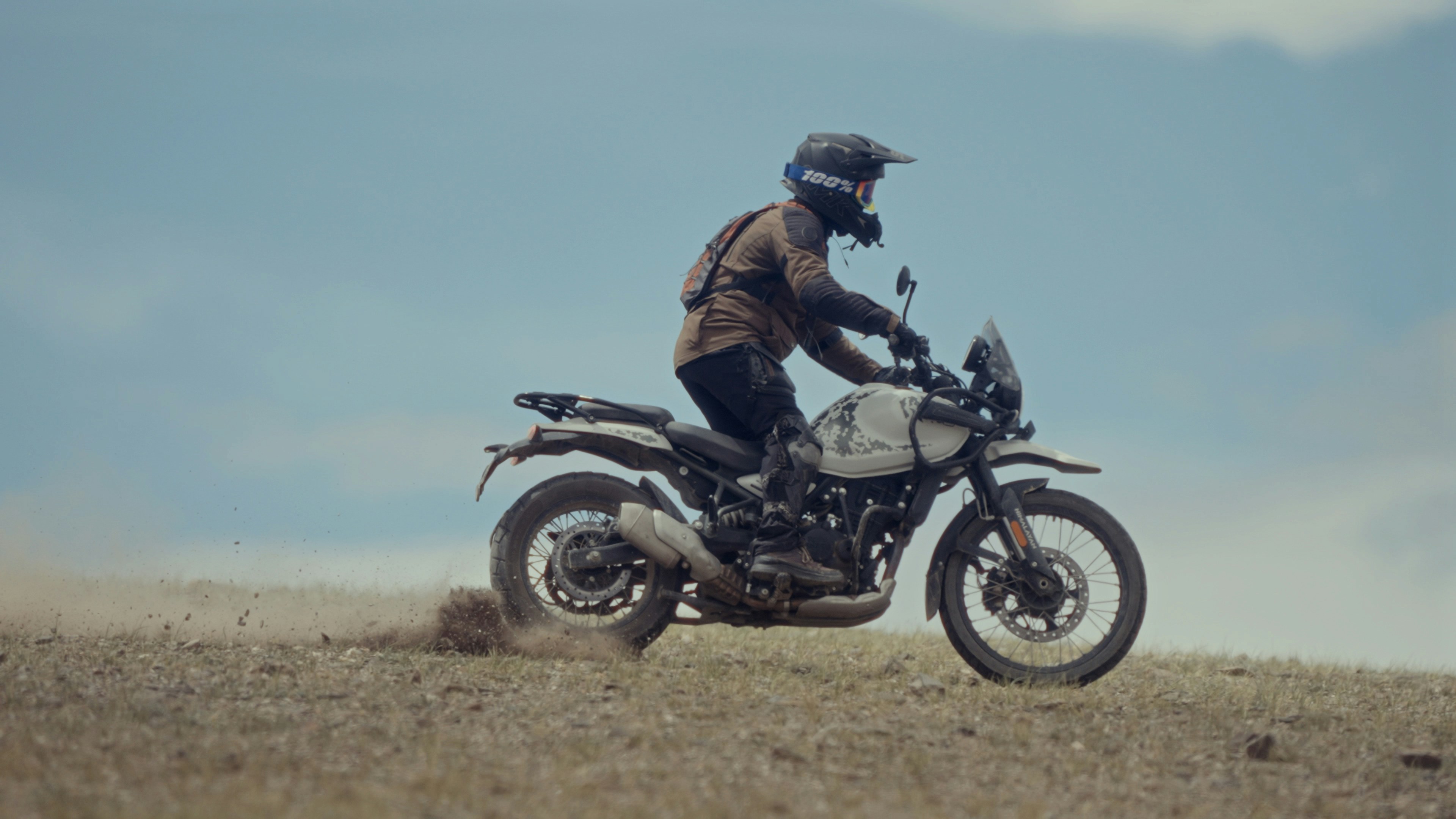 A man riding a motorcycle on top of a dry grass field