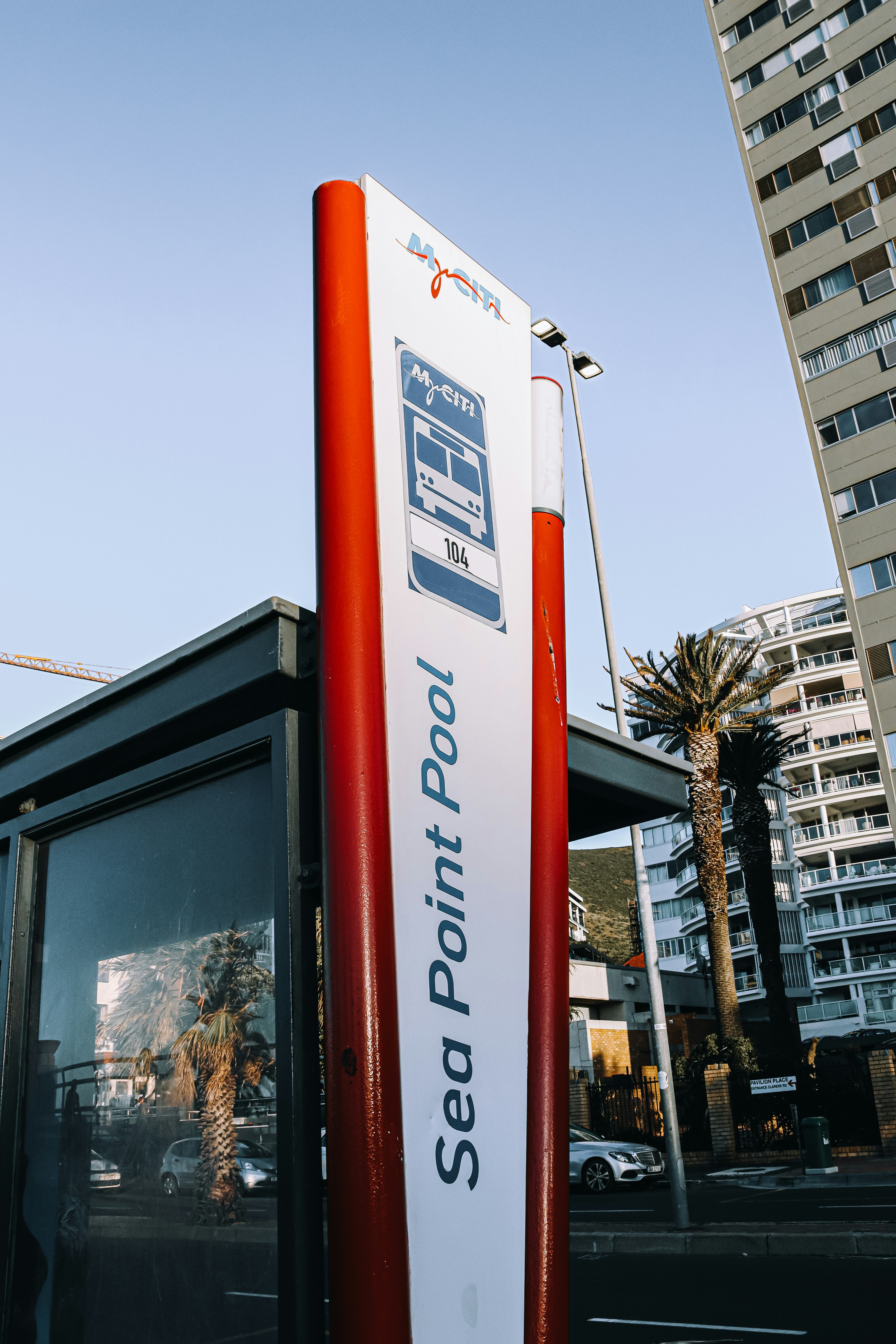 A red and white bus stop sitting next to a tall building