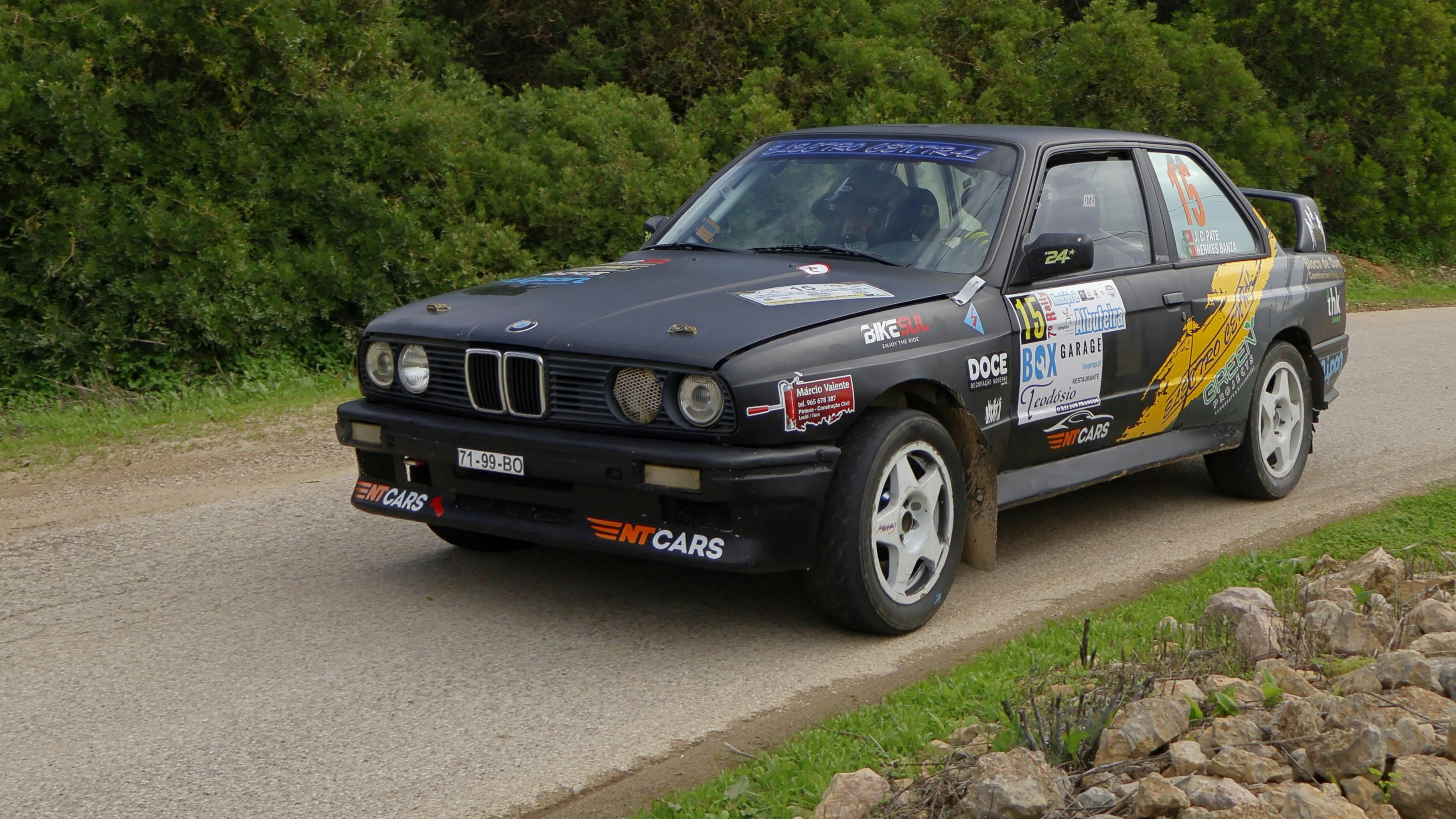A black car driving down a road next to a forest