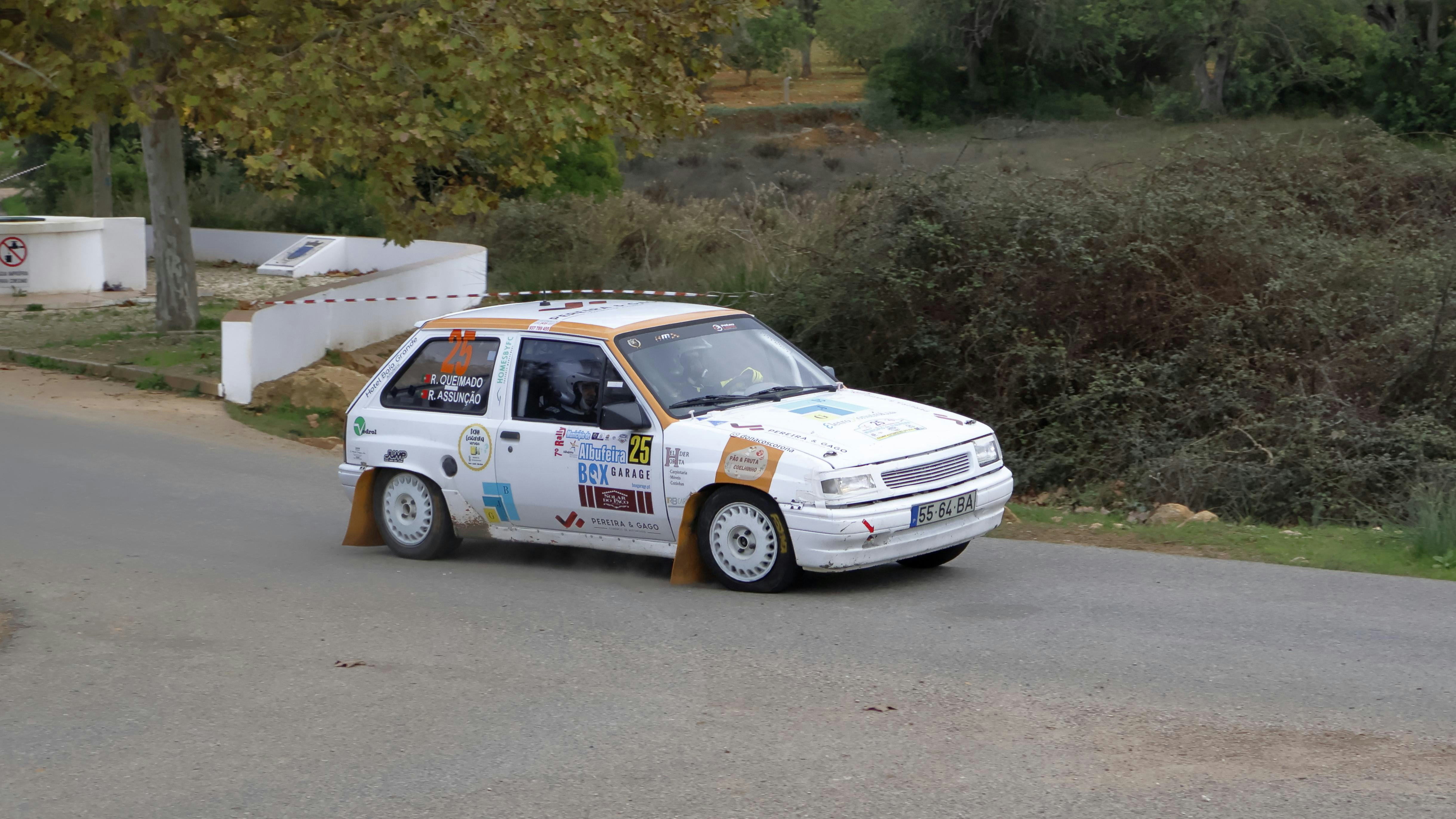 A small white car driving down a street