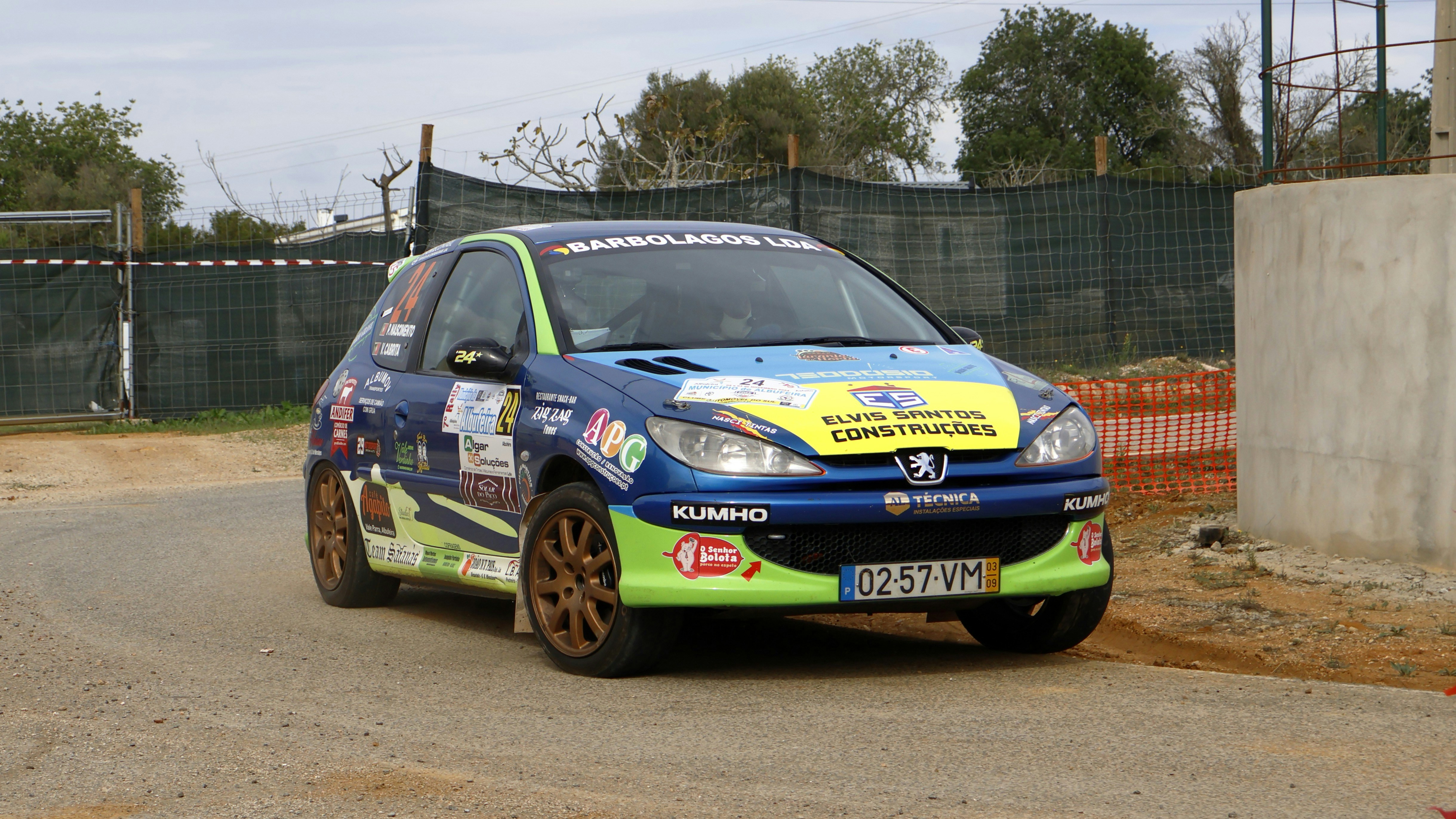 A blue and yellow car driving down a dirt road