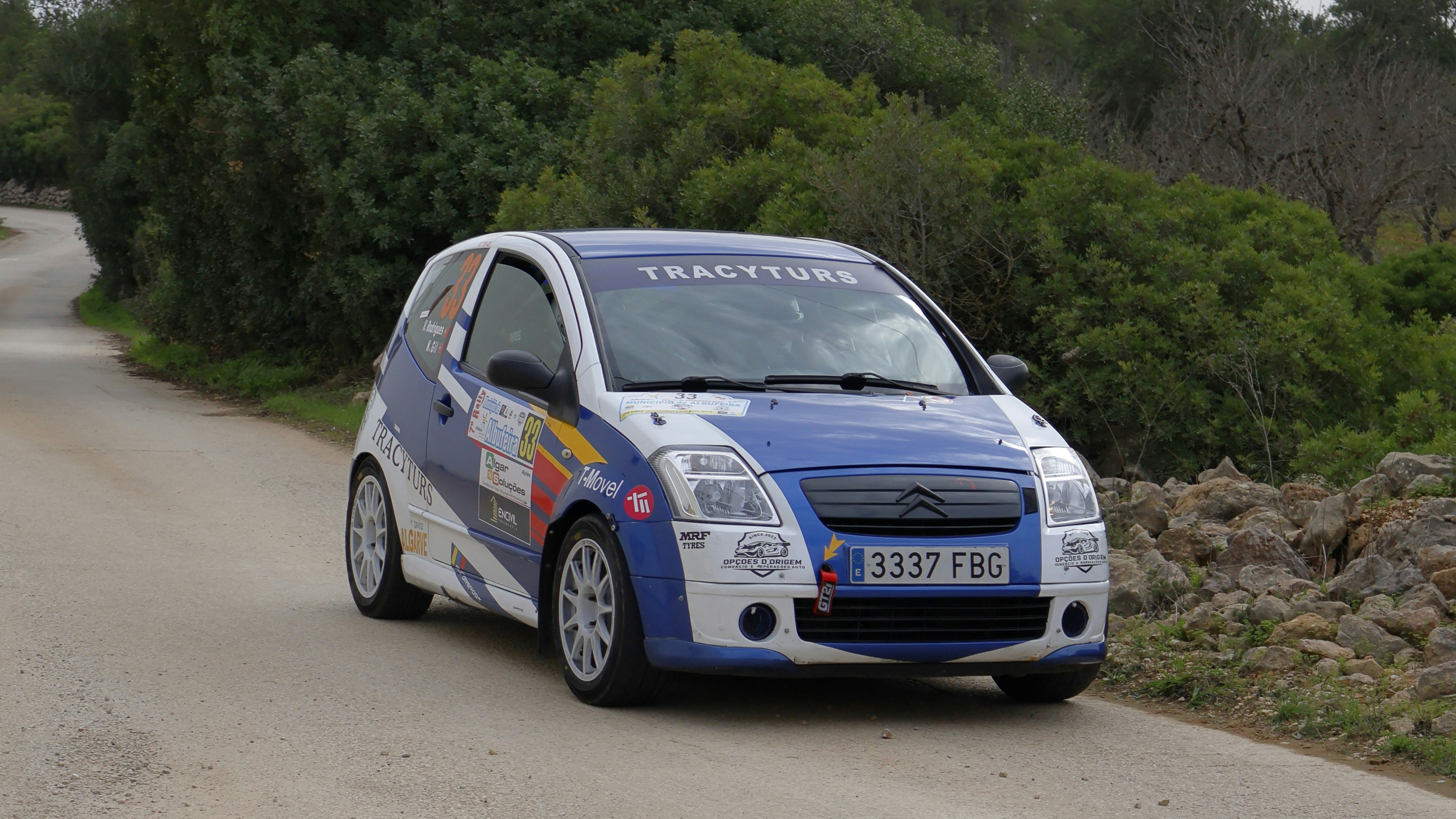 A small blue and white car driving down a road