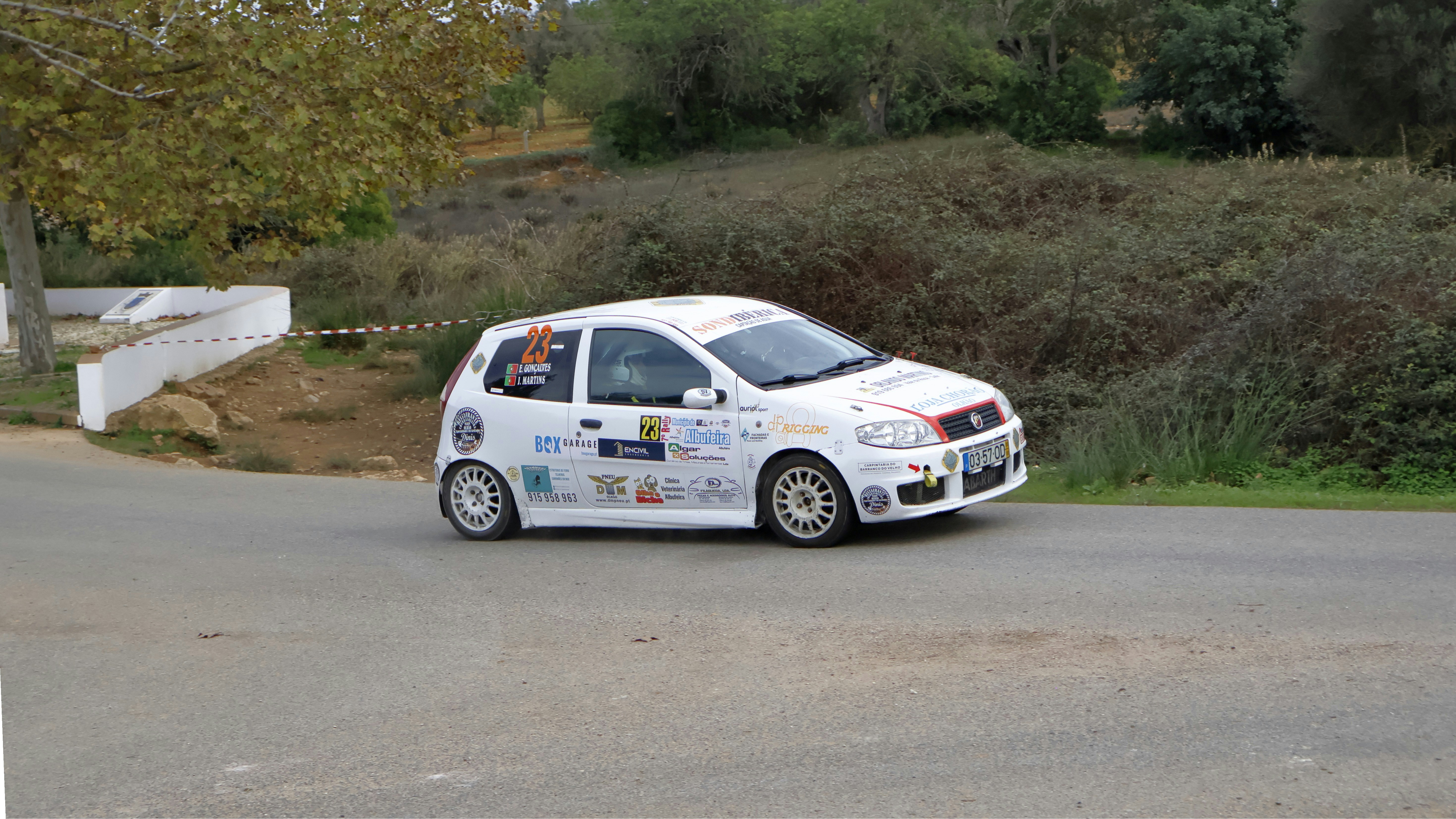 A small white car driving down a street