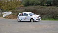A small white car driving down a street