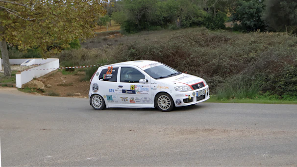 A small white car driving down a street
