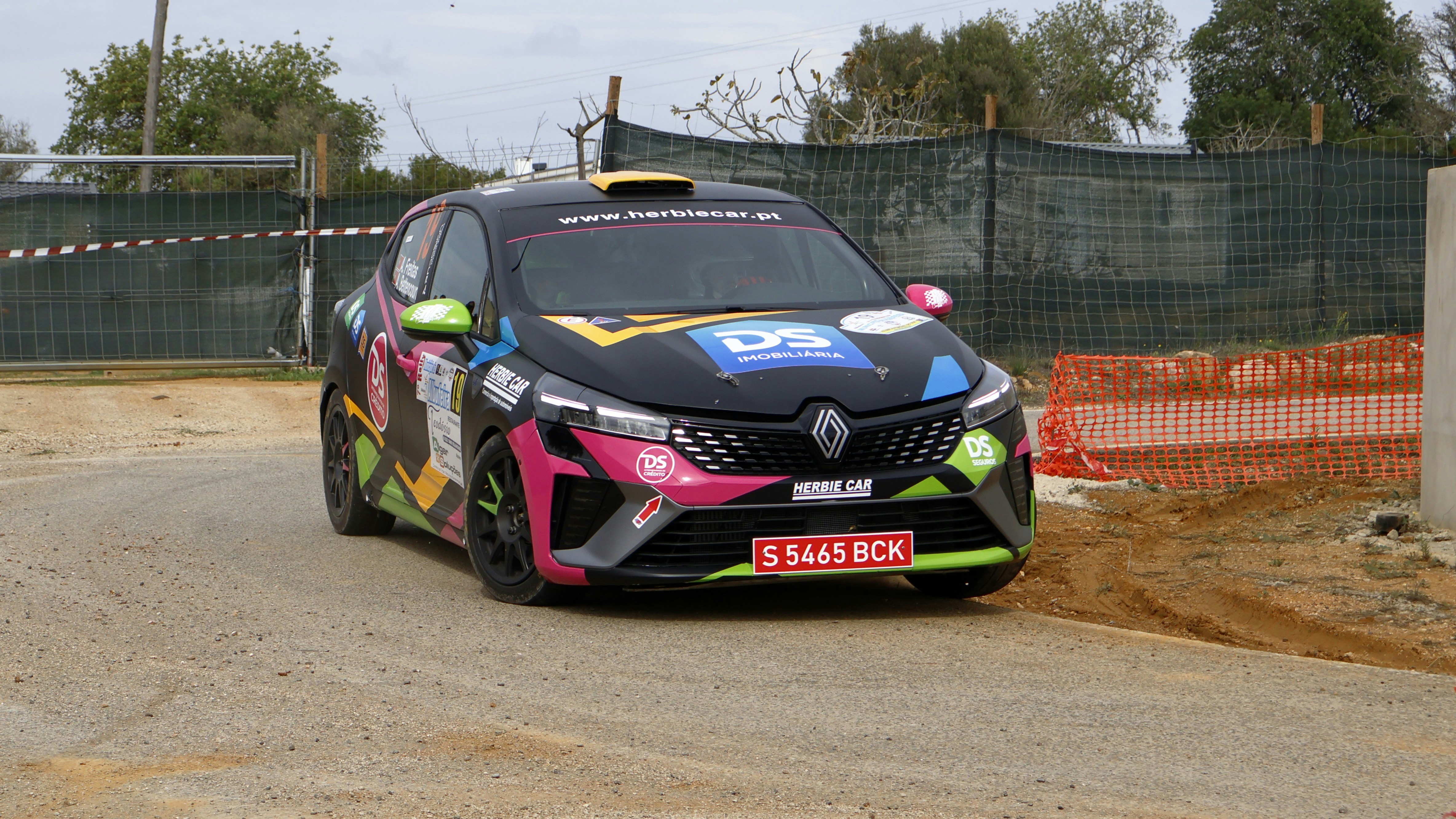 A car driving down a dirt road next to a fence