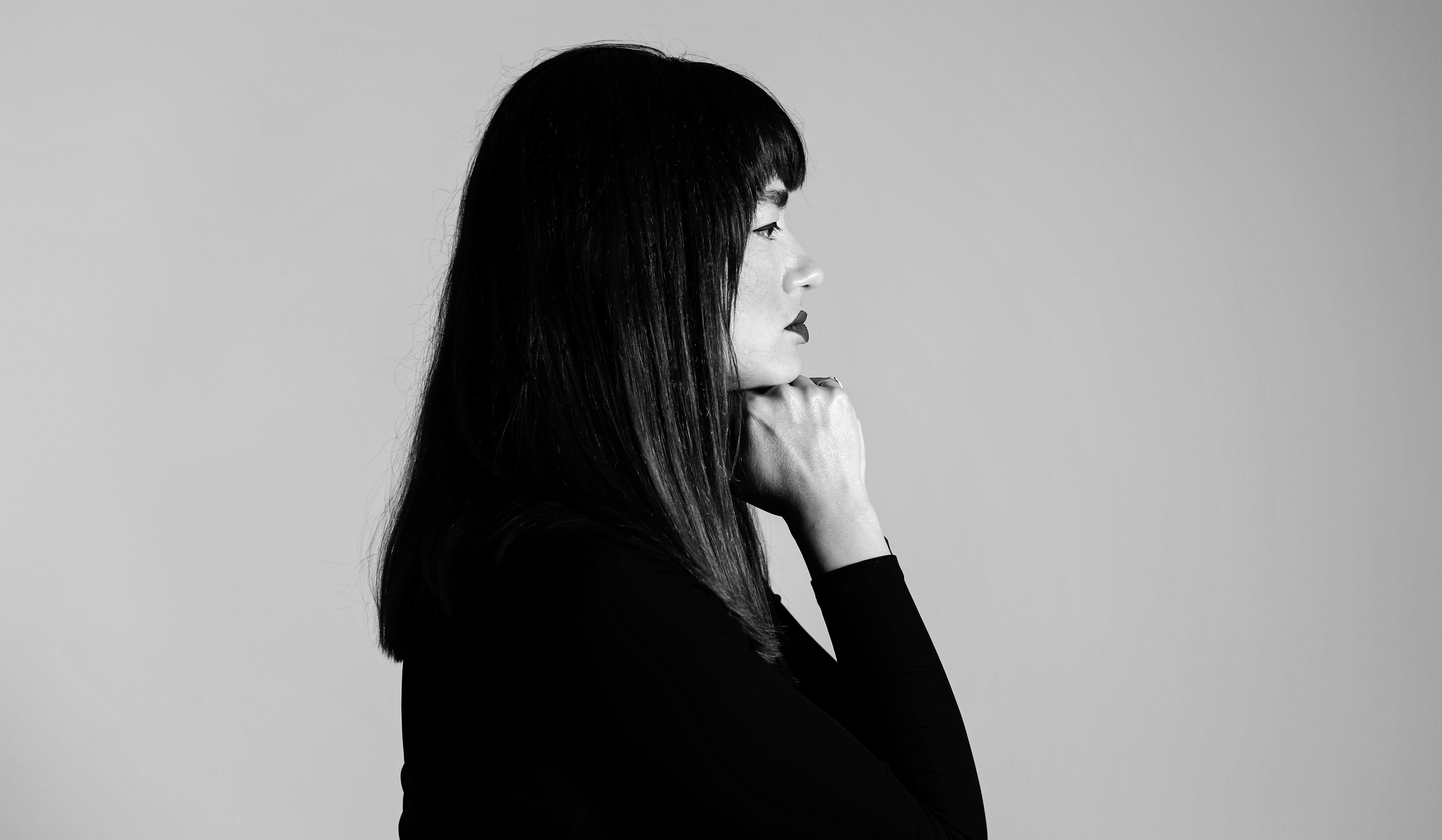 A woman standing in front of a mirror with her hand on her chin