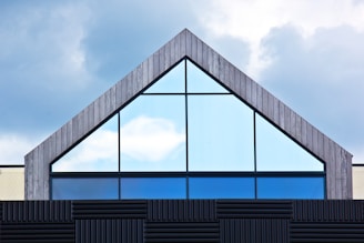 A building with a triangular roof and a sky background