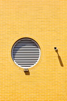 A yellow brick wall with a round window