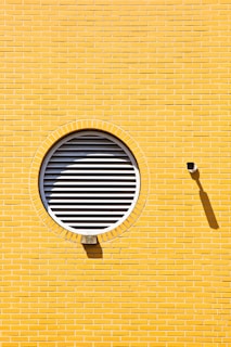 A yellow brick wall with a round window