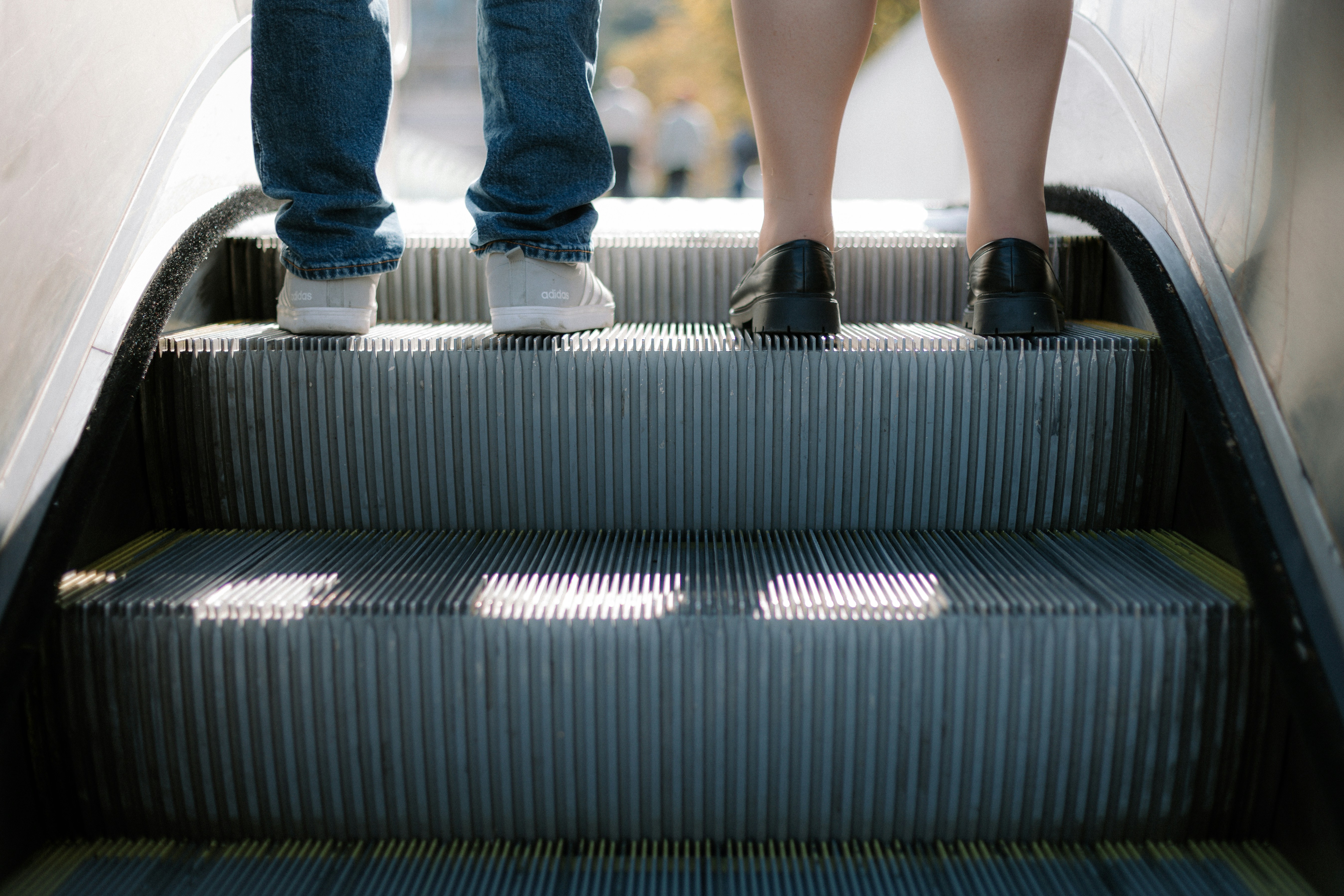 Un hombre y una mujer de pie en una escalera mecánica
