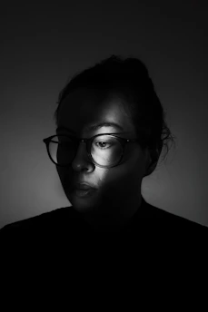 A man wearing glasses in a dark room