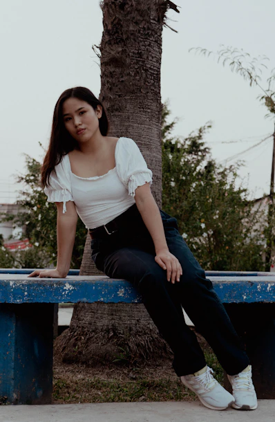 A woman sitting on a blue bench next to a tree
