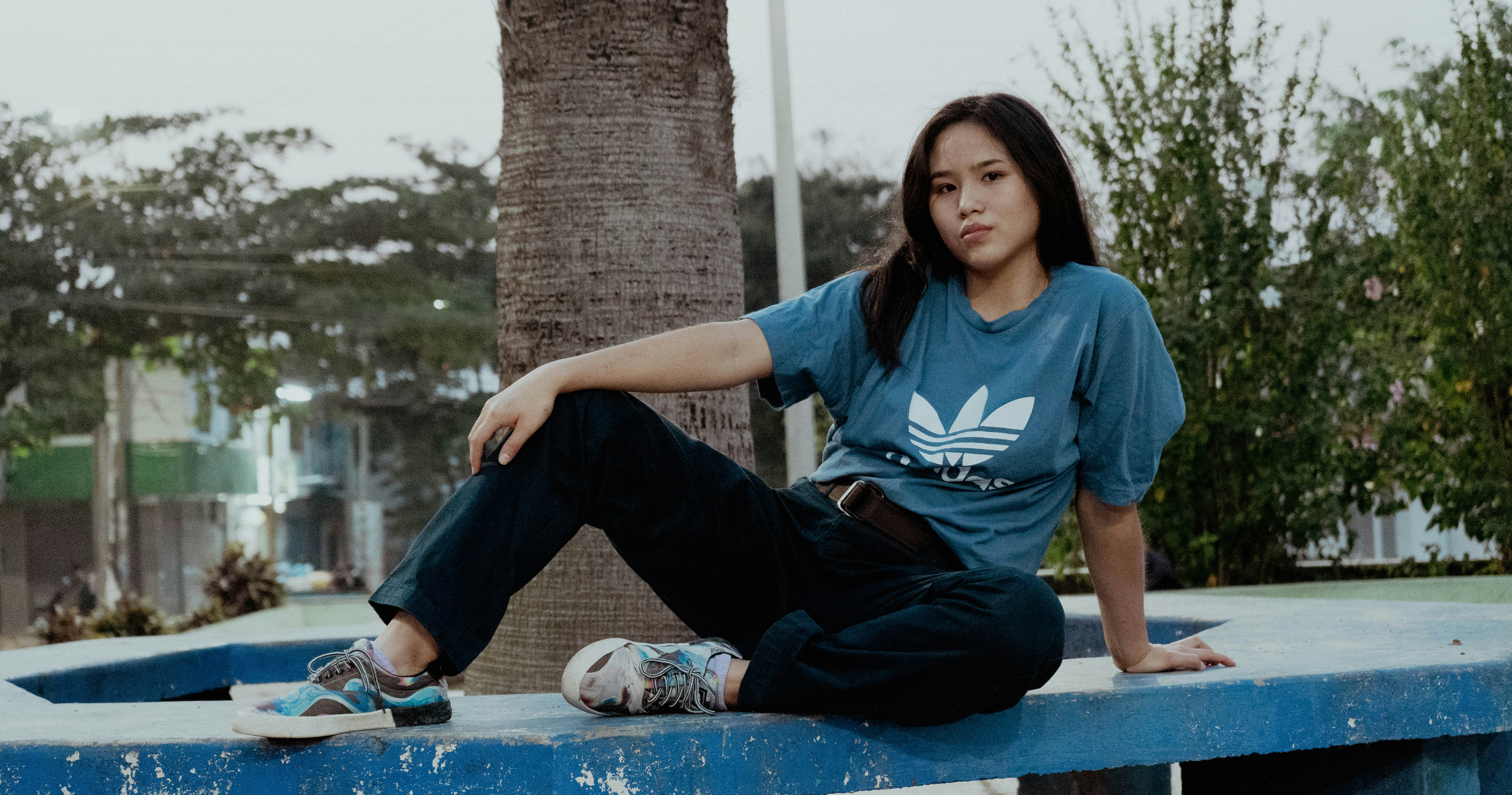 A woman sitting on a blue bench with a skateboard