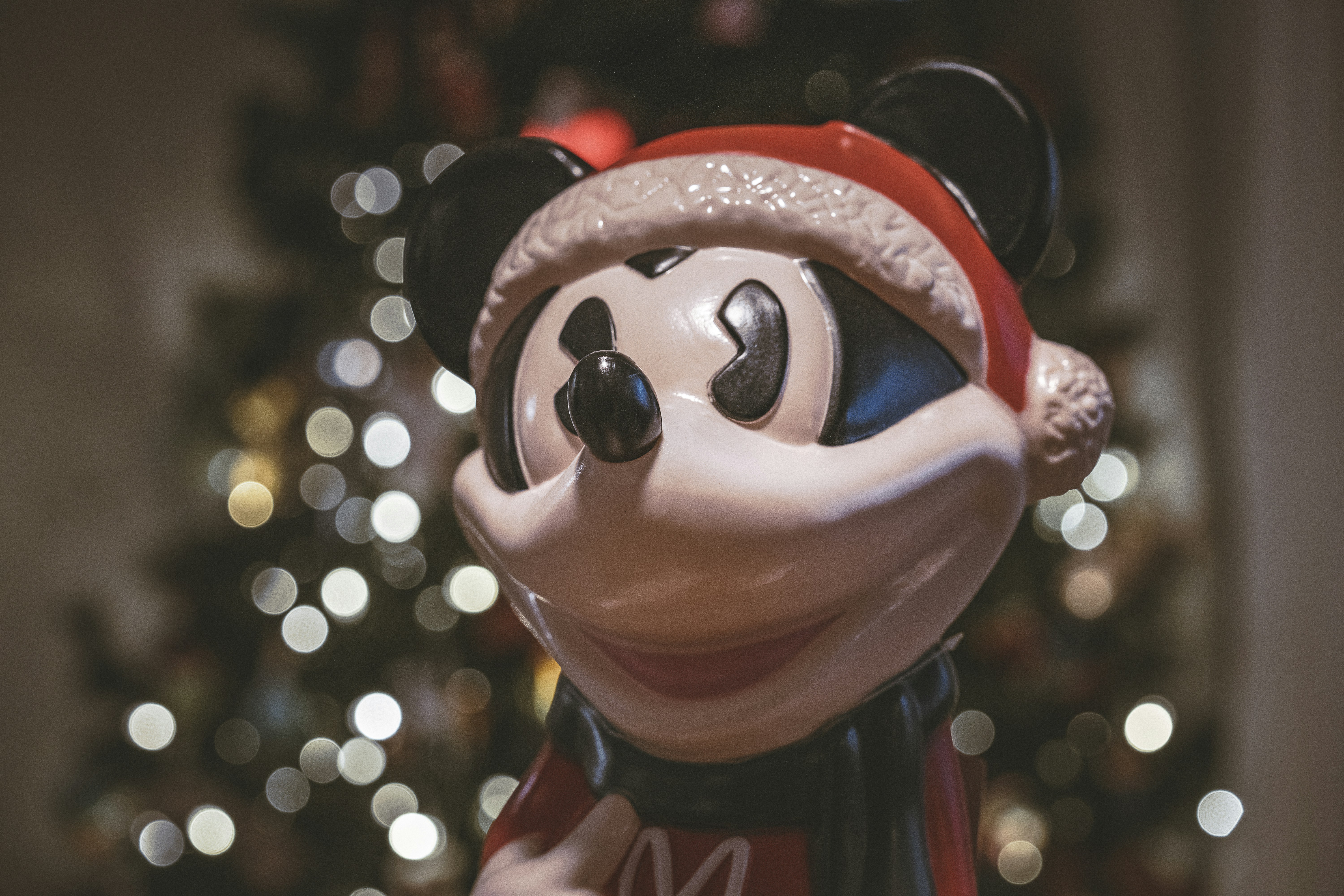 A mickey mouse figurine with a christmas tree in the background