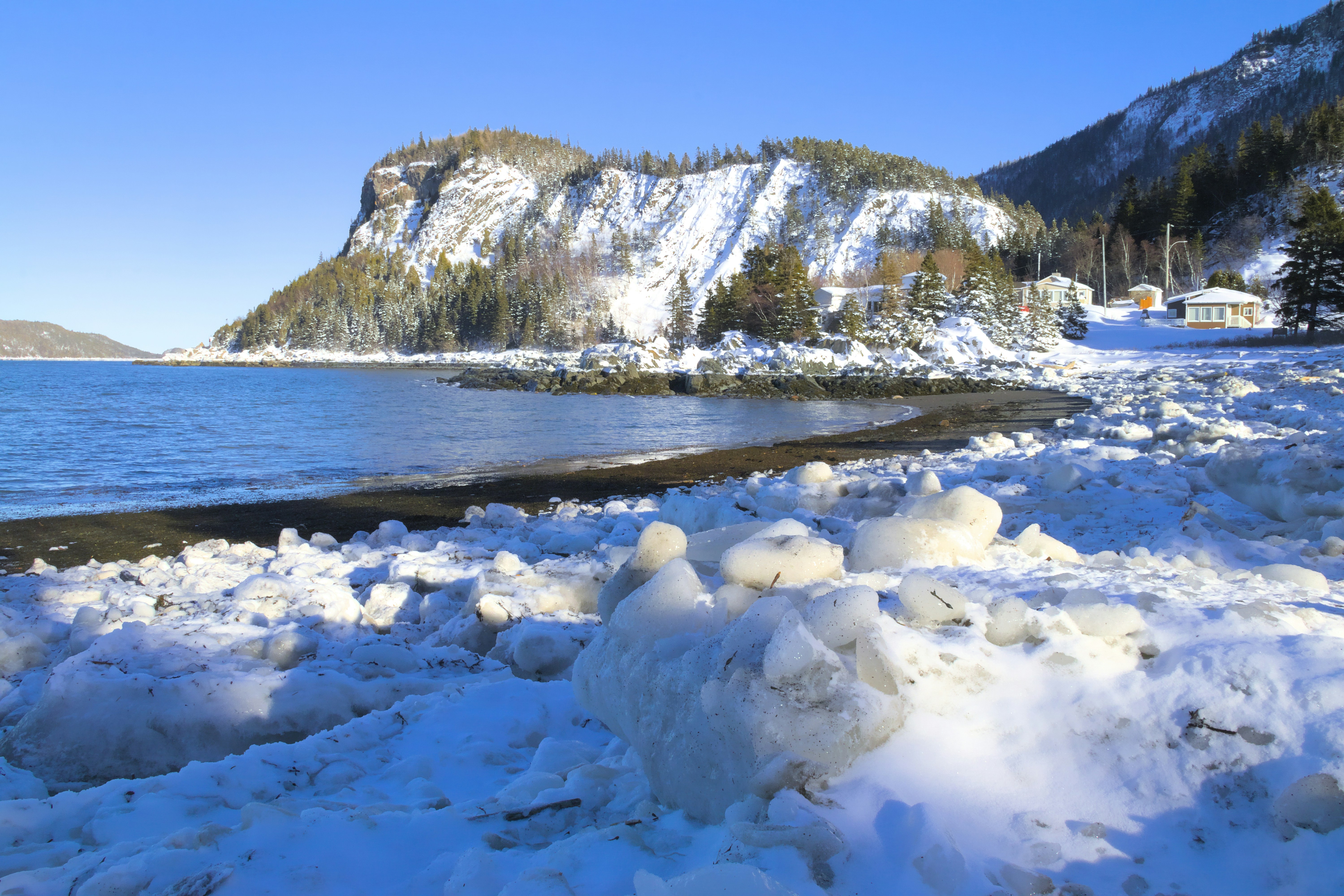 A body of water surrounded by snow covered mountains