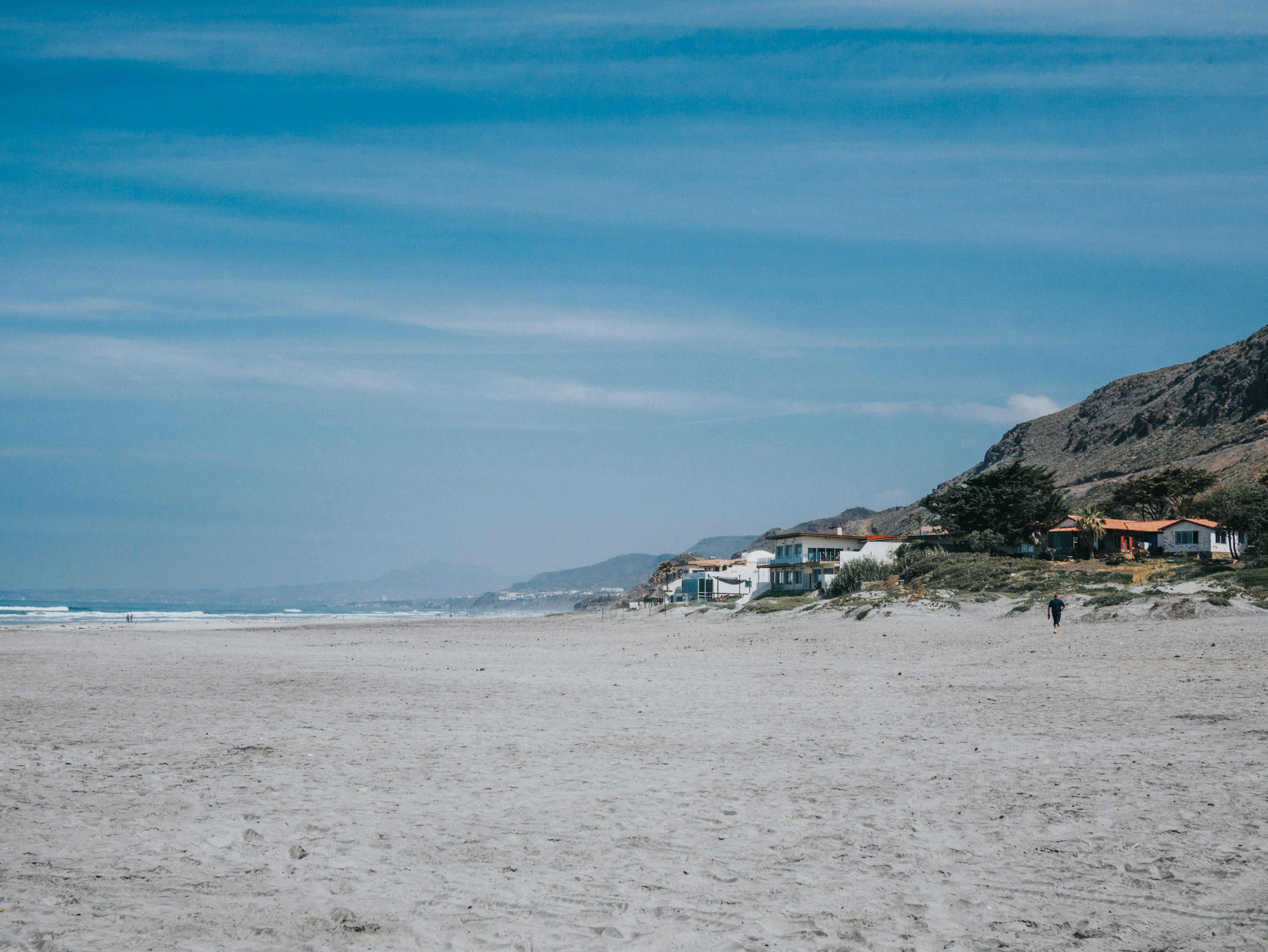 A sandy beach with houses on a hill in the distance