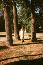 A woman walking a dog through a park