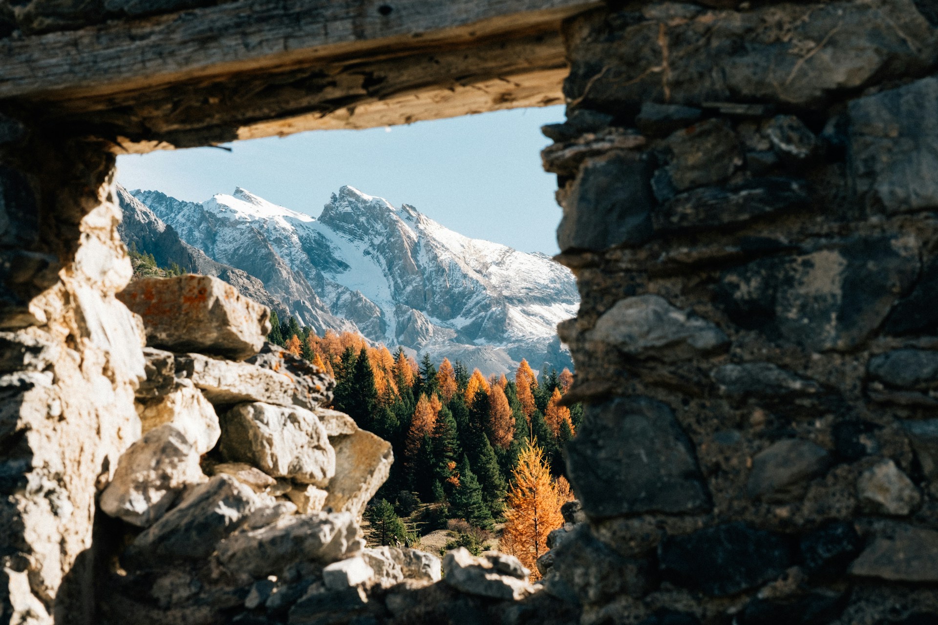 A window in a stone wall with a view of a mountain range