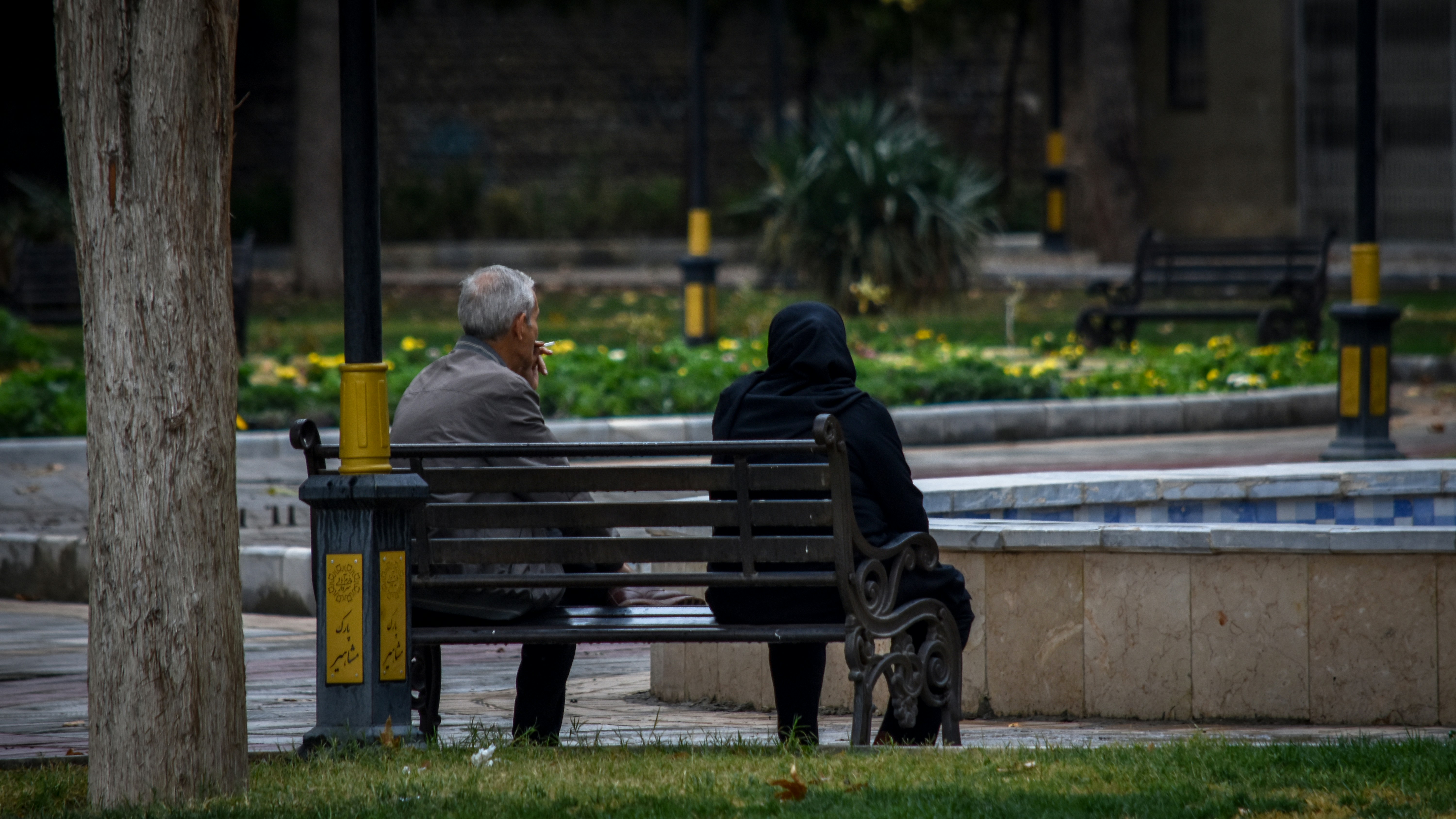 A man and a woman sitting on a park bench