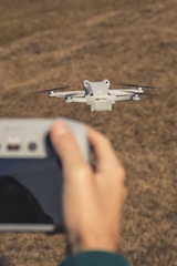 A person holding a remote control in front of a flying object