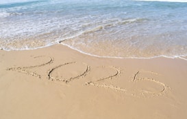 A sandy beach with the word summer written in the sand