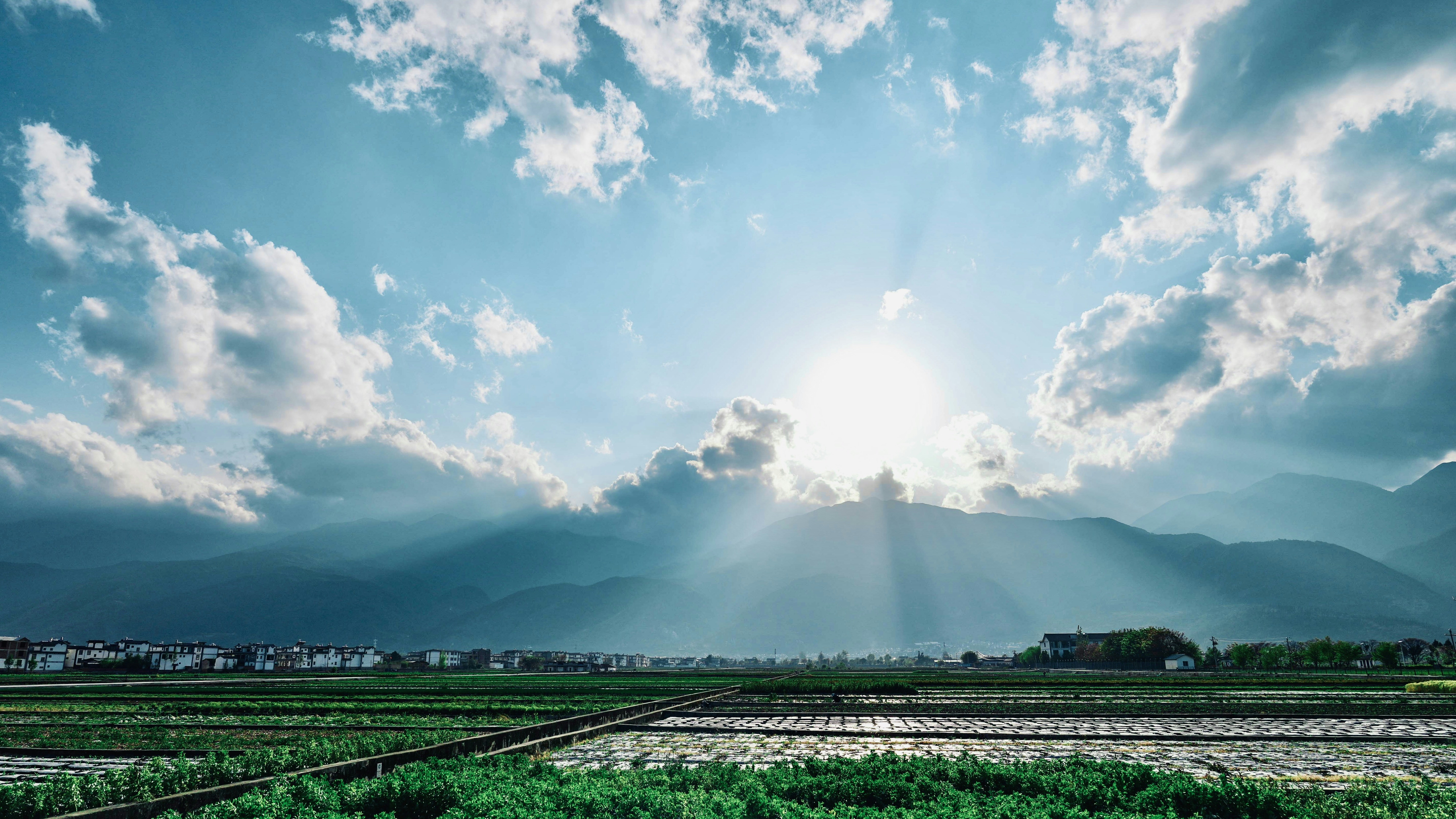 The sun shining through the clouds over a field photo – Free Blue Image ...