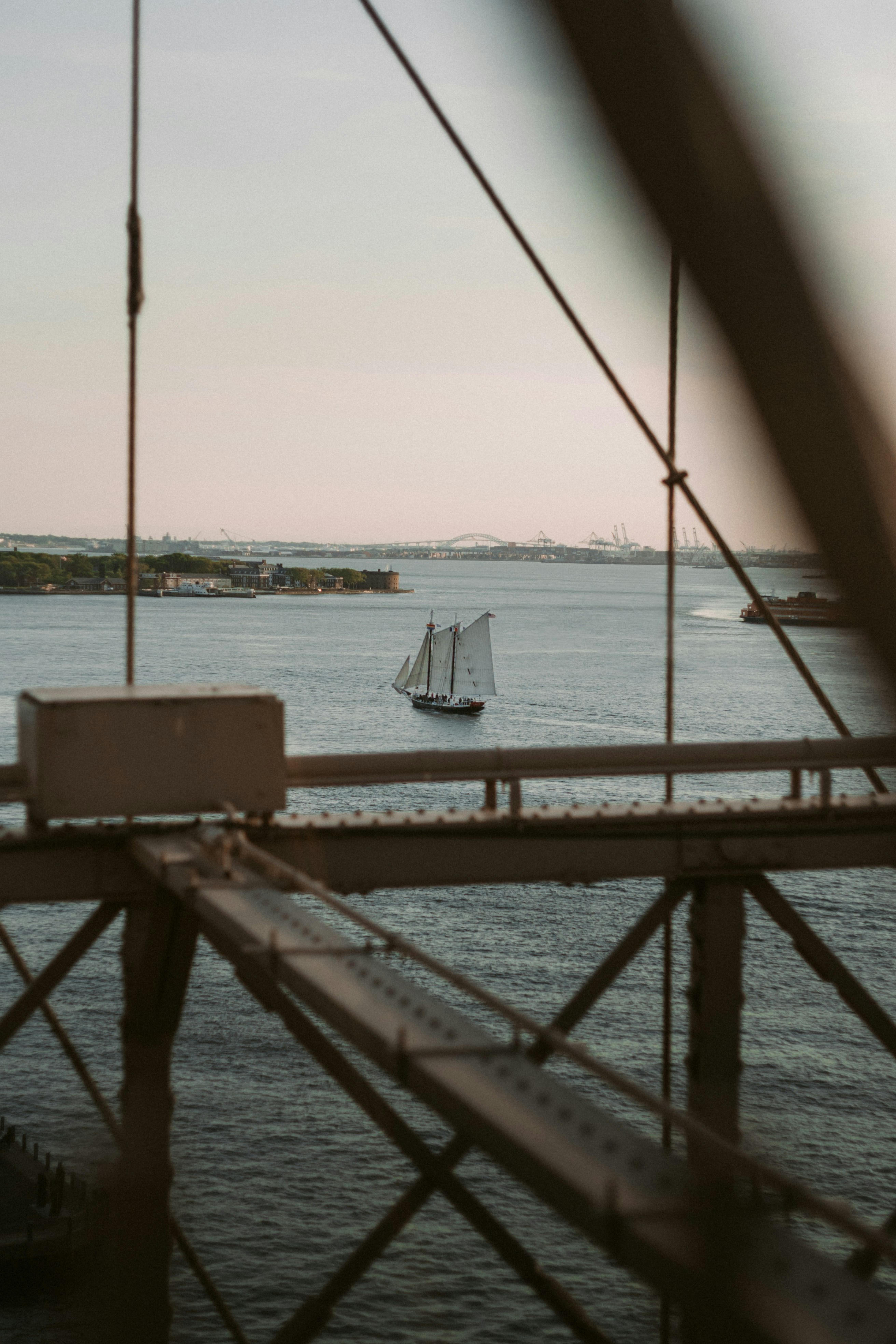 A boat is sailing on the water near a bridge