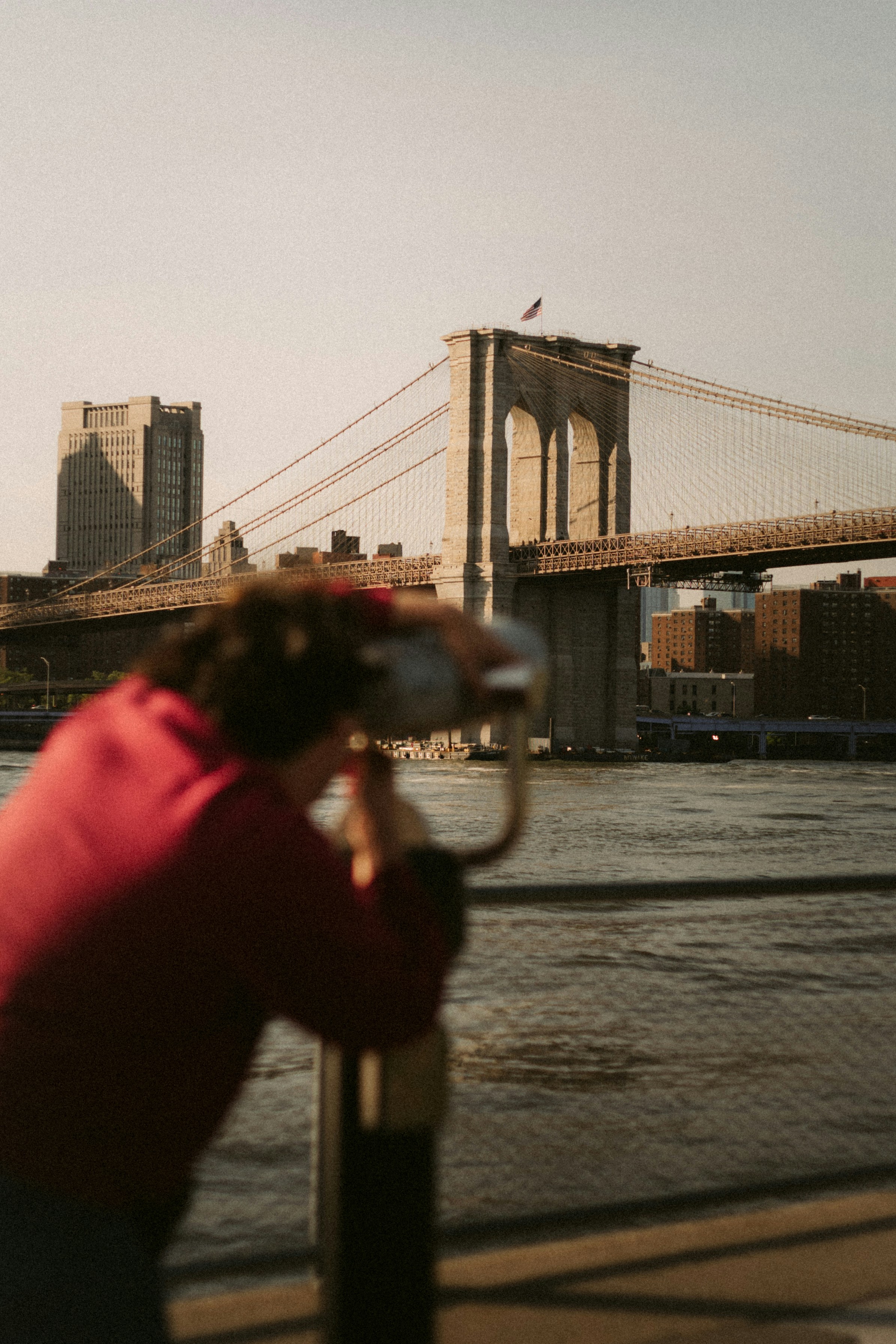A woman is taking a picture of the brooklyn bridge