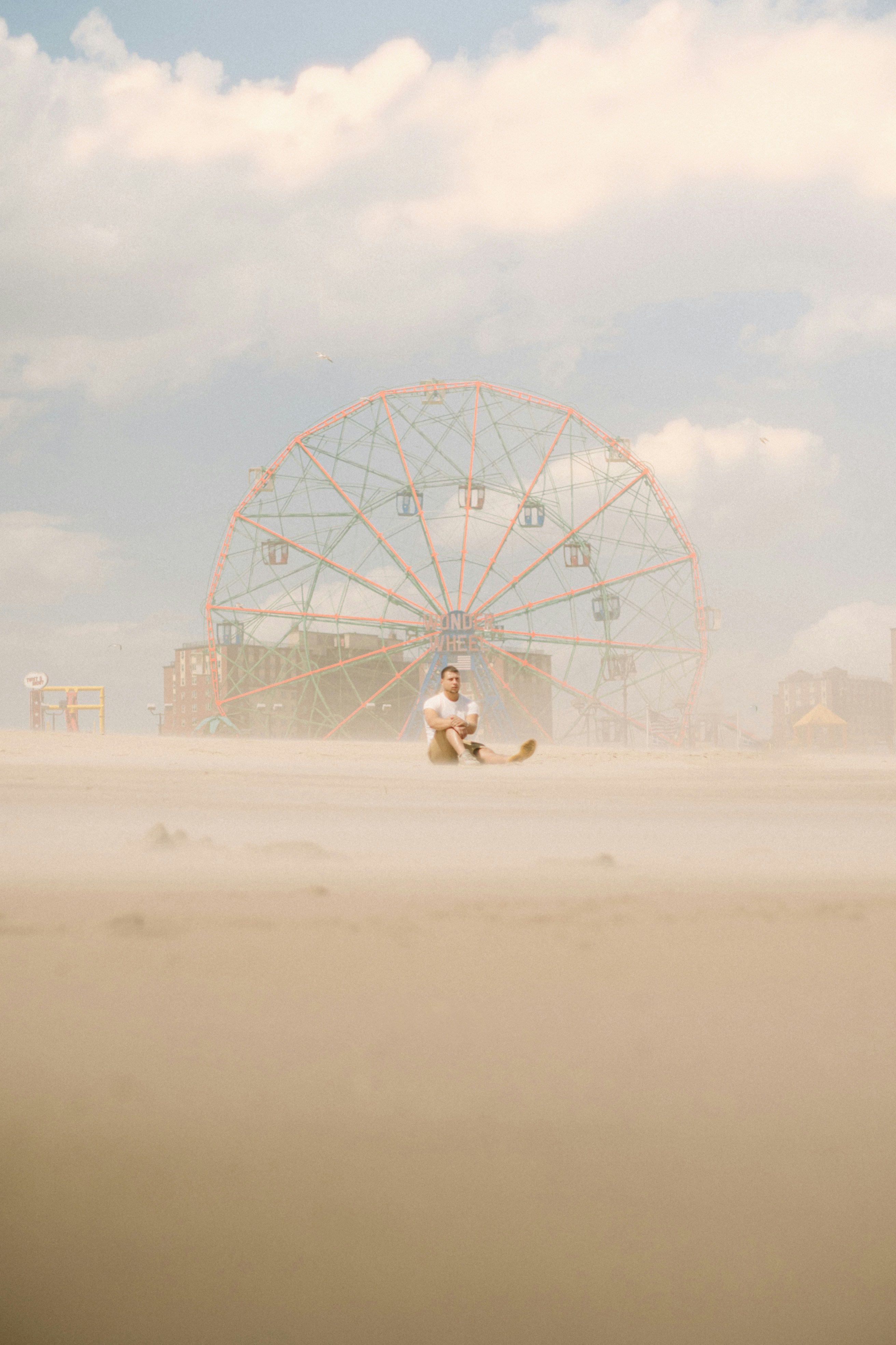 A person running on a beach near a ferris wheel