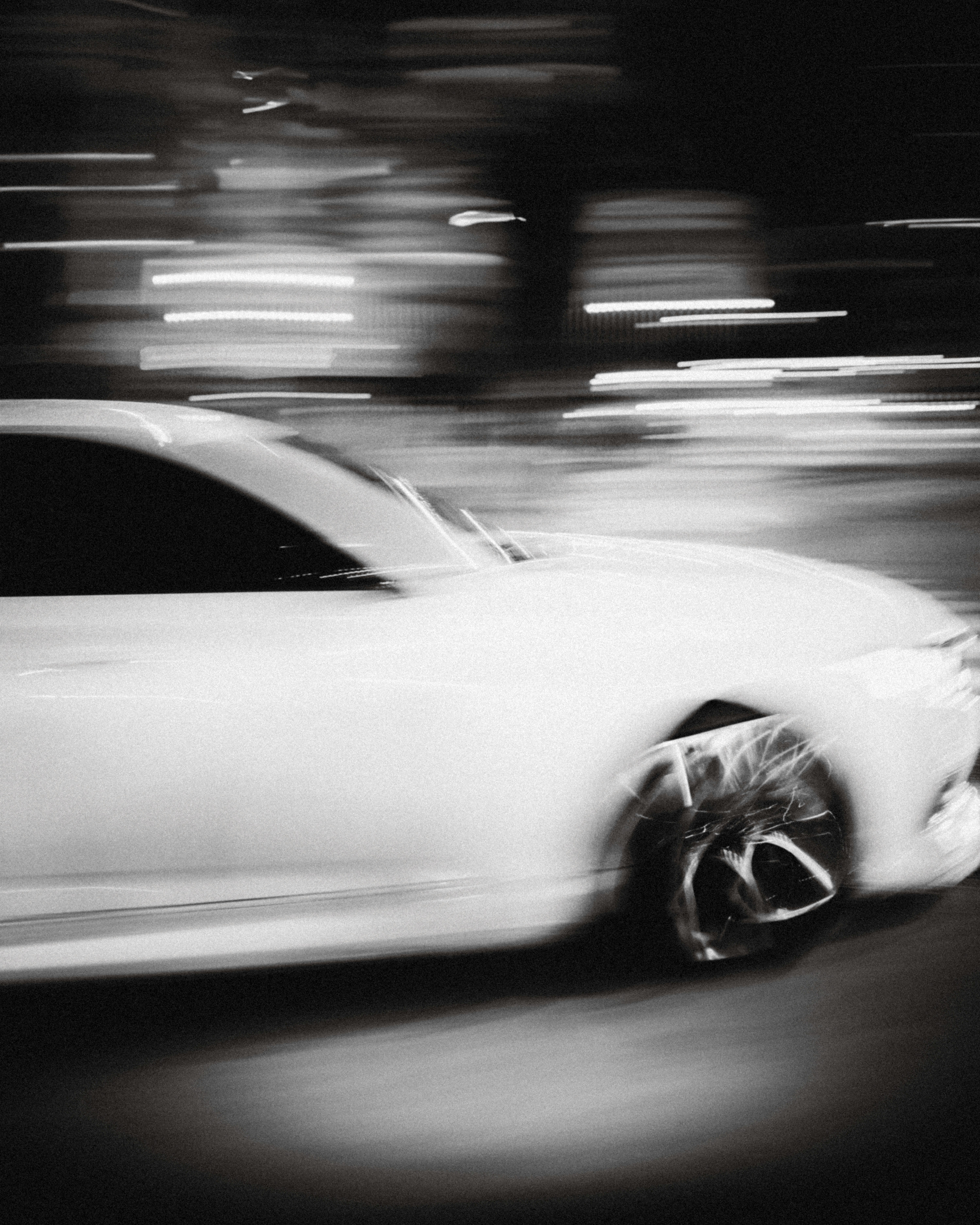 A white car driving down a street at night