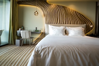 A bedroom with a white bed and a wooden headboard