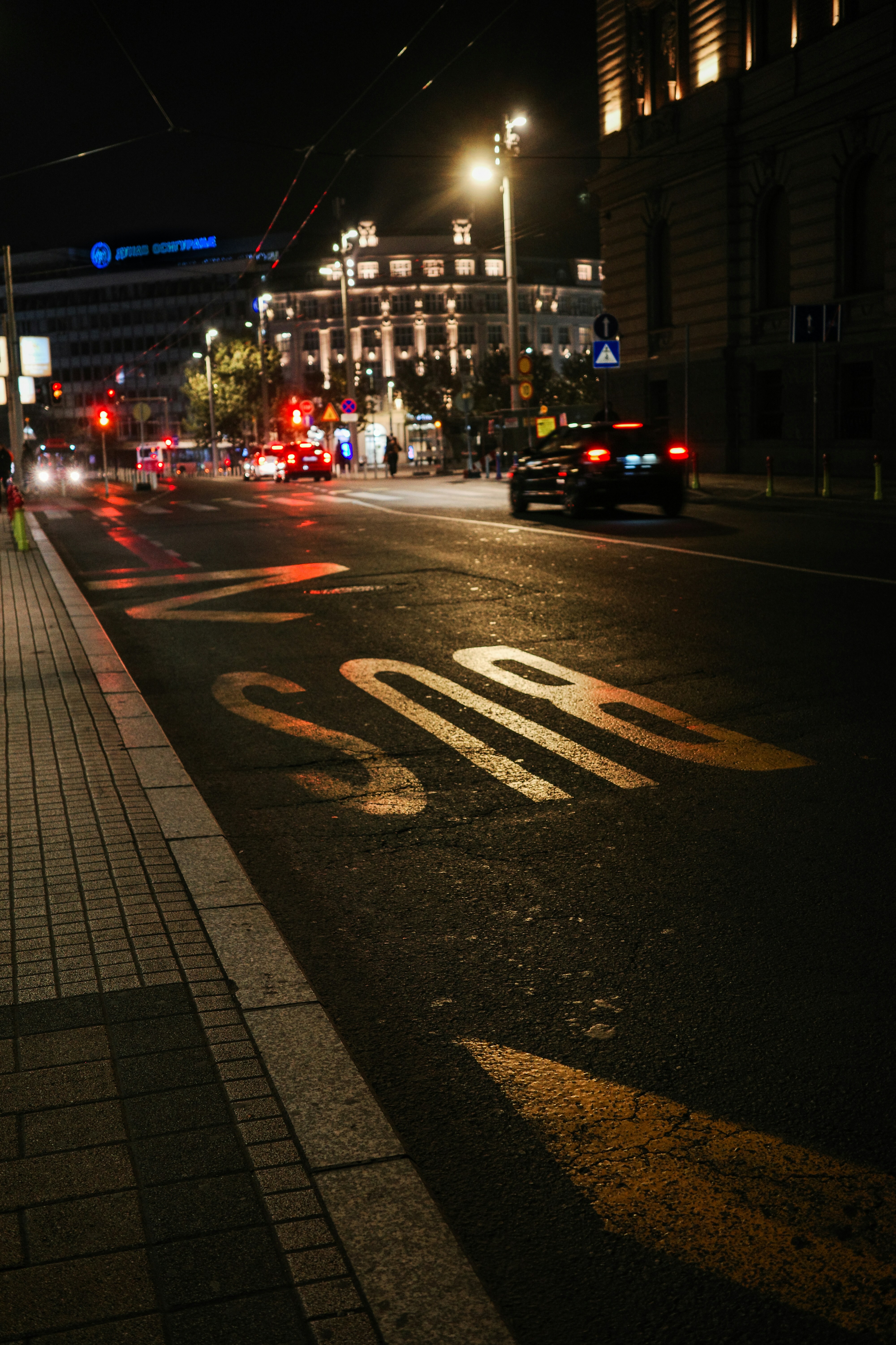 A city street at night with cars driving on it photo – Free Car Image ...