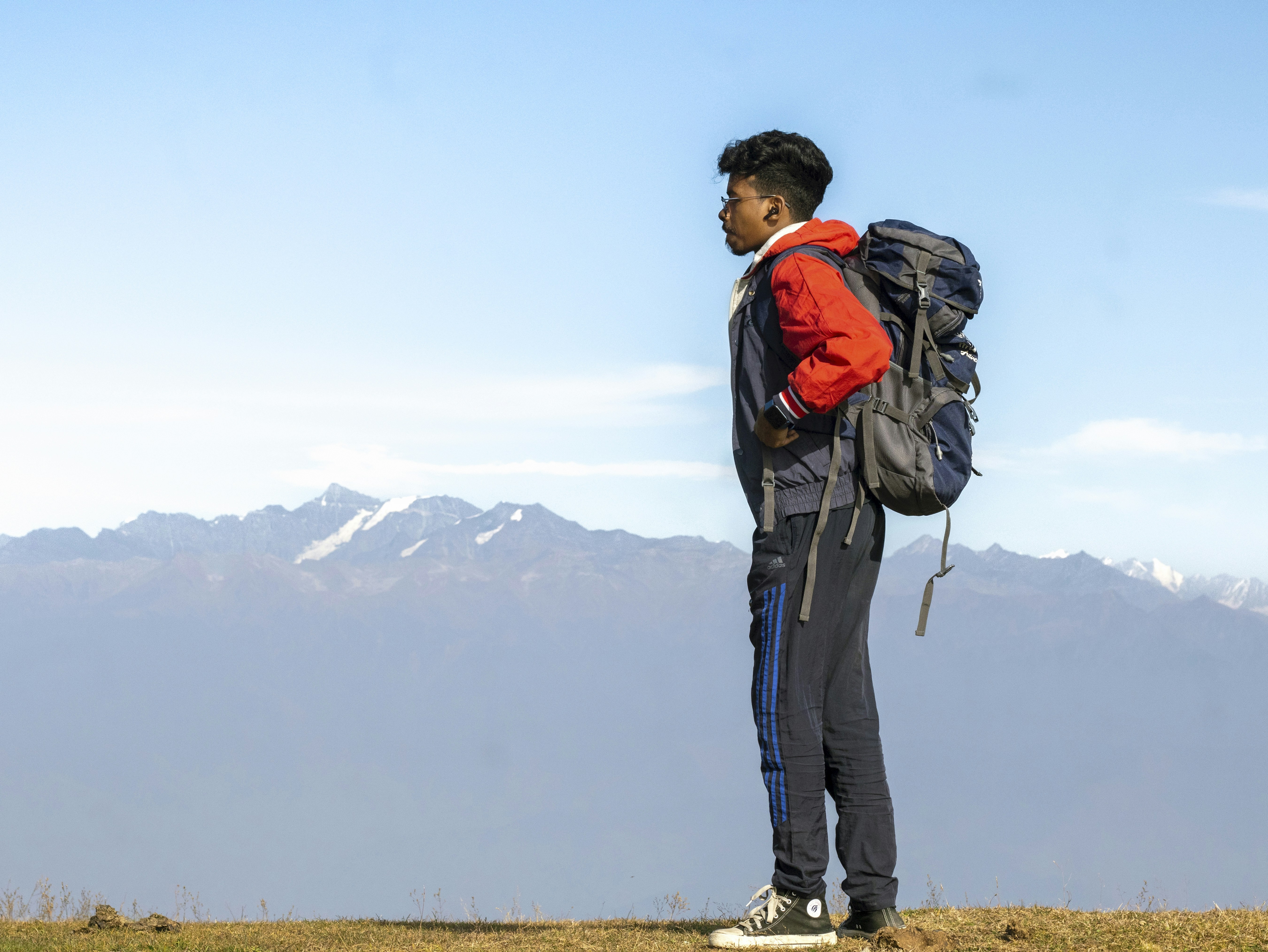 A man standing on top of a hill with a backpack, 