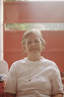 An older woman sitting in a chair with a baby seat