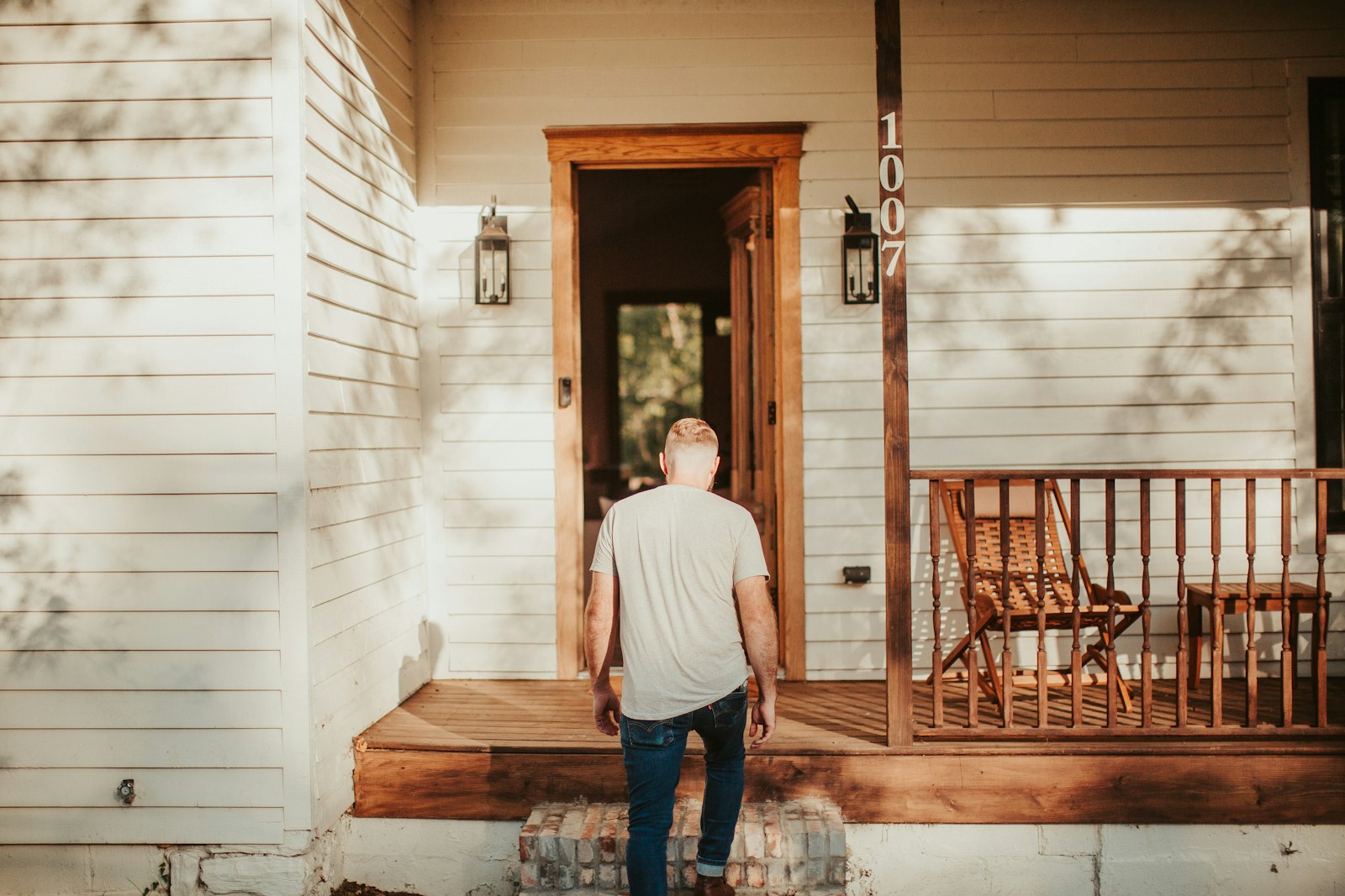 Person standing on the front porch of a home in warm natural light